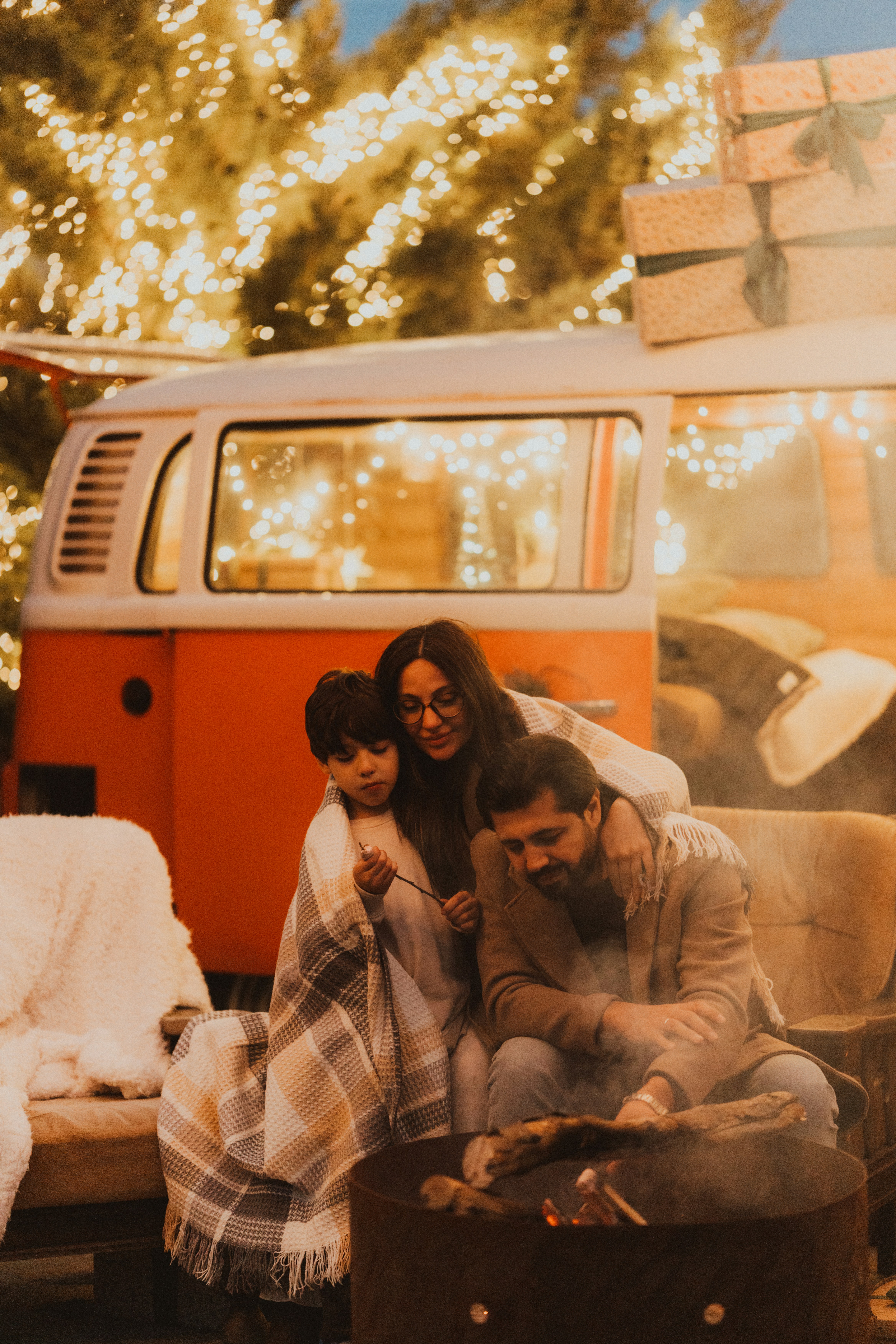 Family gathered around a campfire near a camper van.