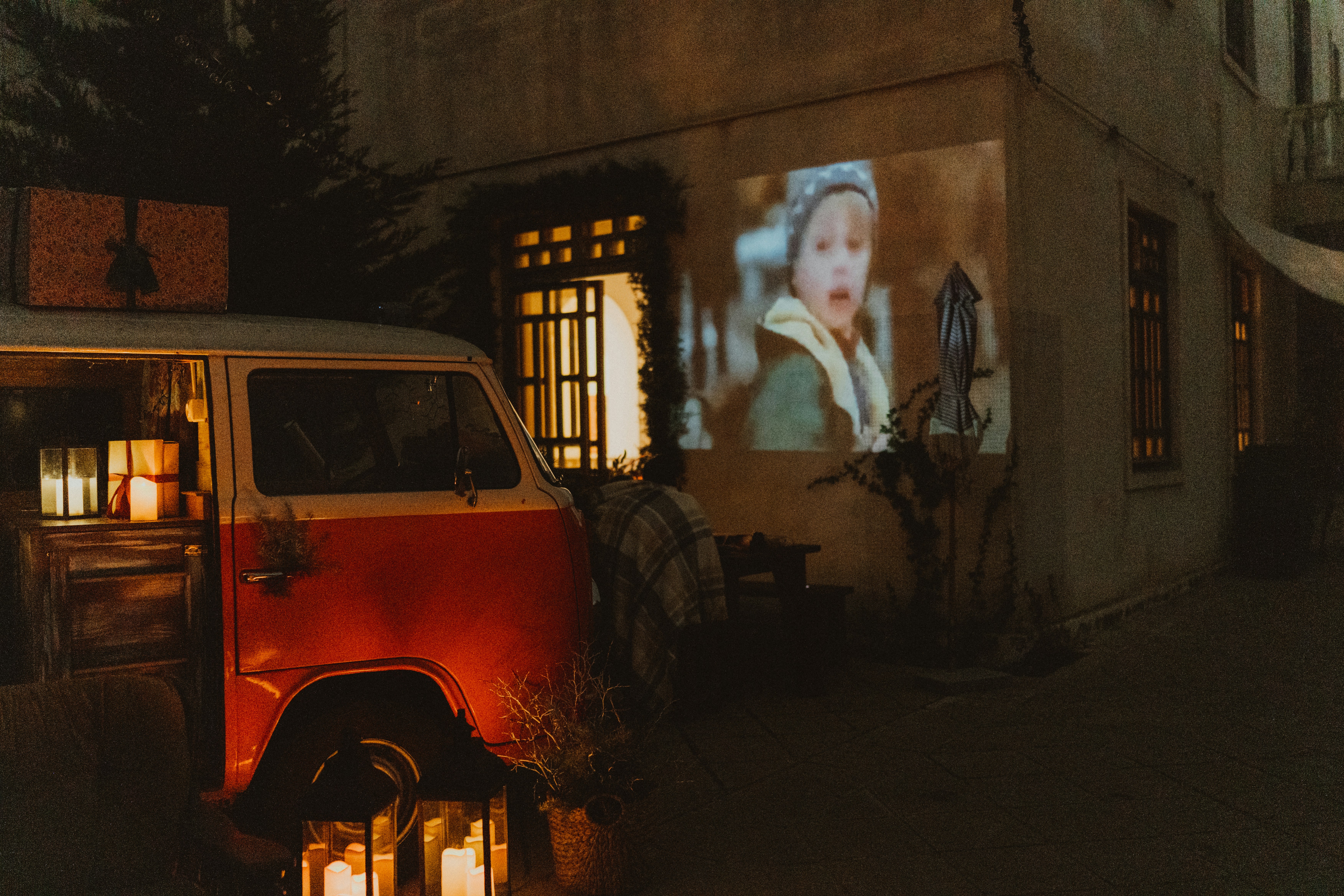 Red van parked outside building with movie projected on wall
