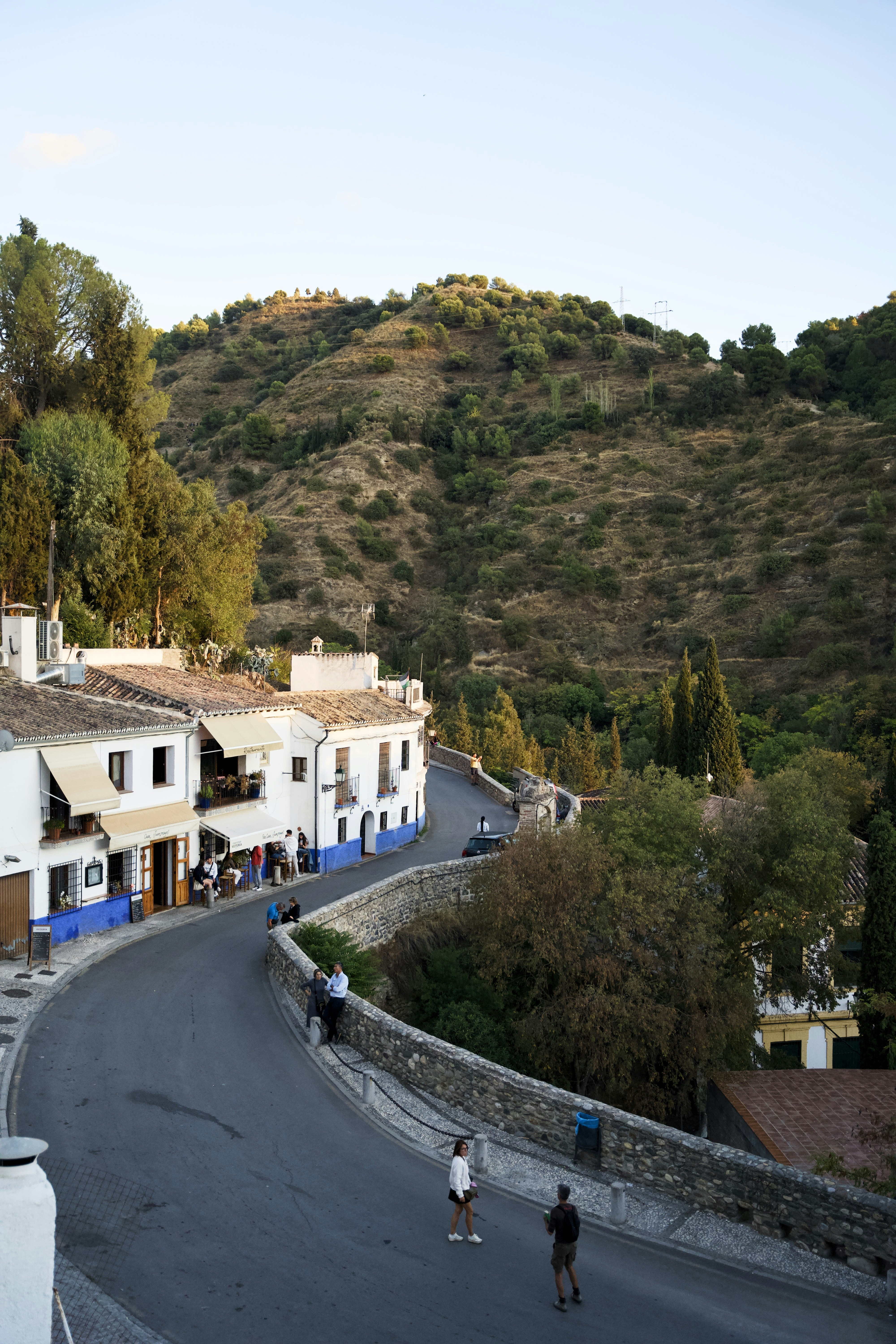 Estrada sinuosa por uma vila com prédios brancos.