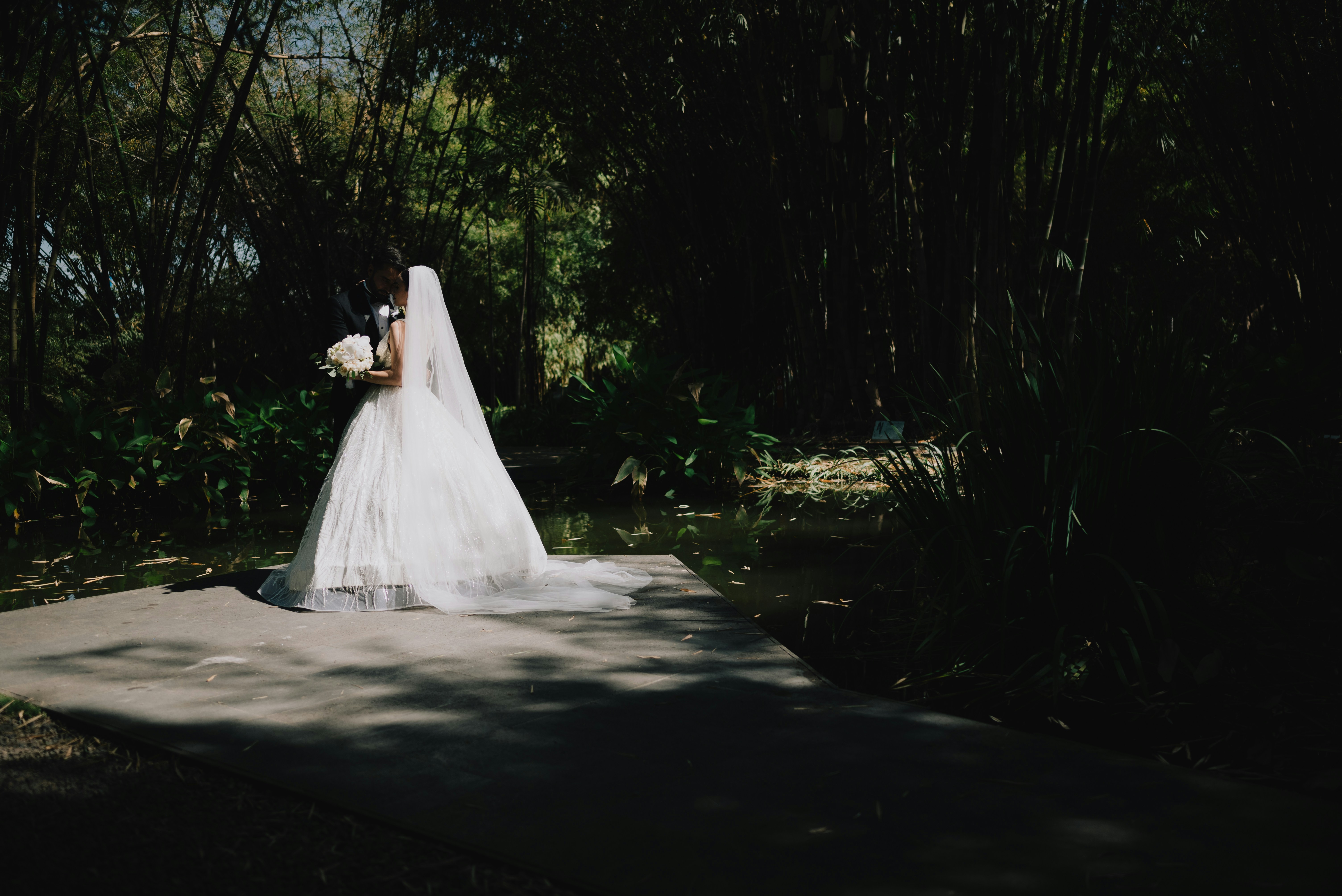 Bride in a white dress holding a bouquet outdoors.