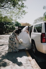 Bride in wedding dress entering limousine with help