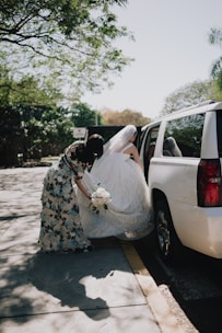 Bride in wedding dress entering limousine with help