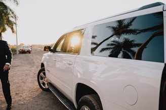 White suv parked on a dirt road at sunset
