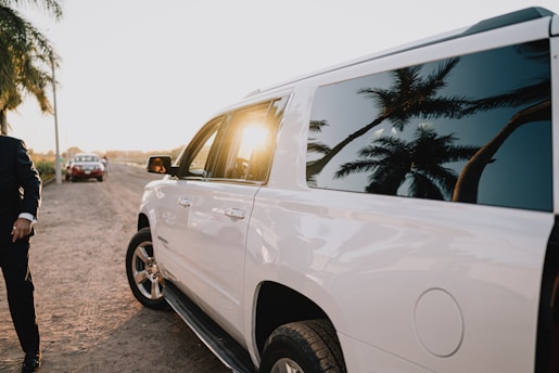 White suv parked on a dirt road at sunset