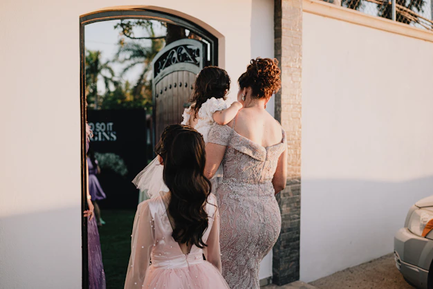 Woman carries child through doorway with girls following girls