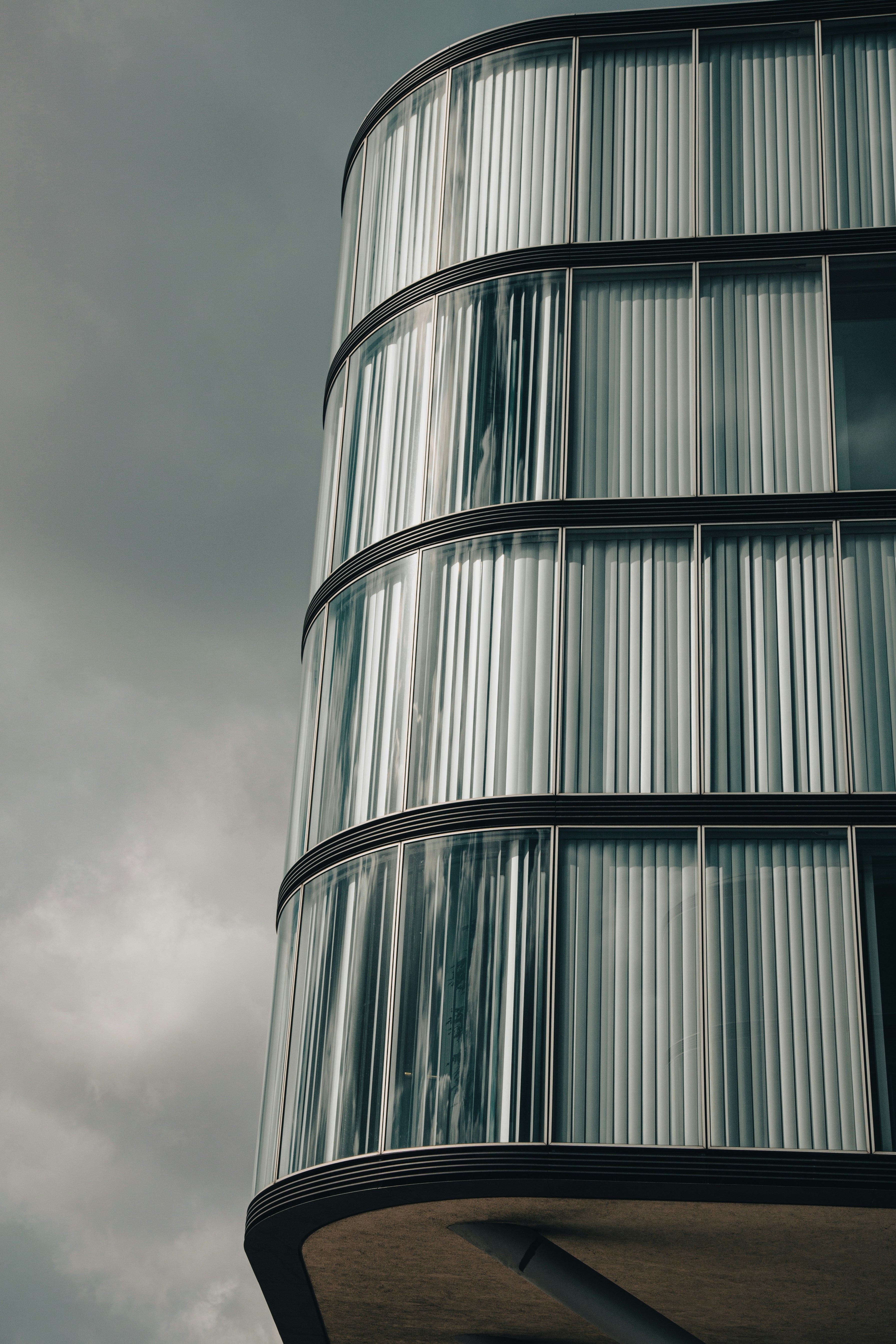 Modernes Gebäude mit gebogenen Glasfenstern und Vorhängen.