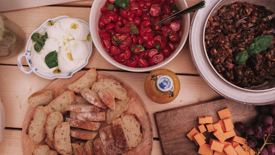 A spread of bread, cheese, tomatoes, and dips.
