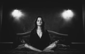 Woman meditating cross-legged on a bed