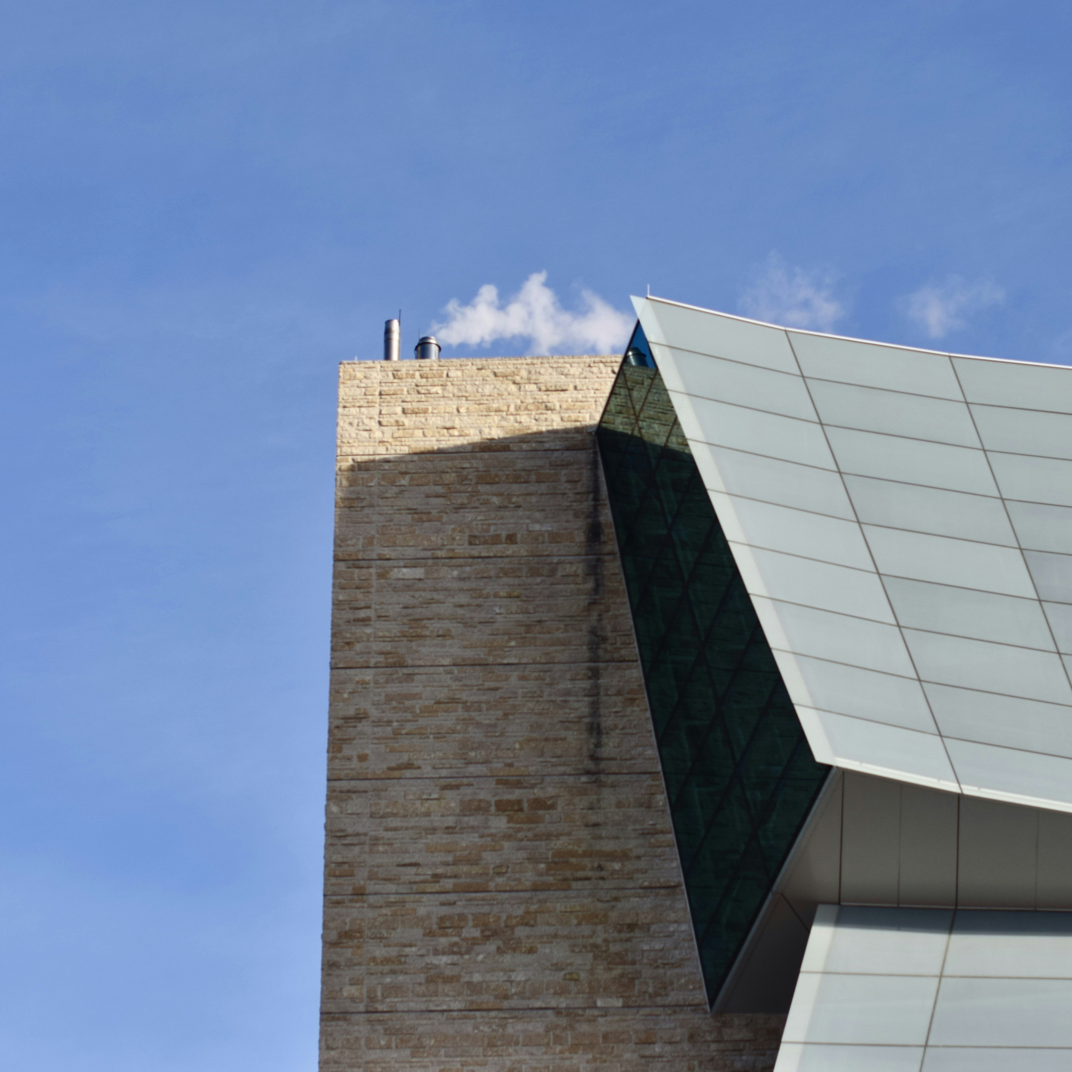 Modern building with geometric glass facade against blue sky