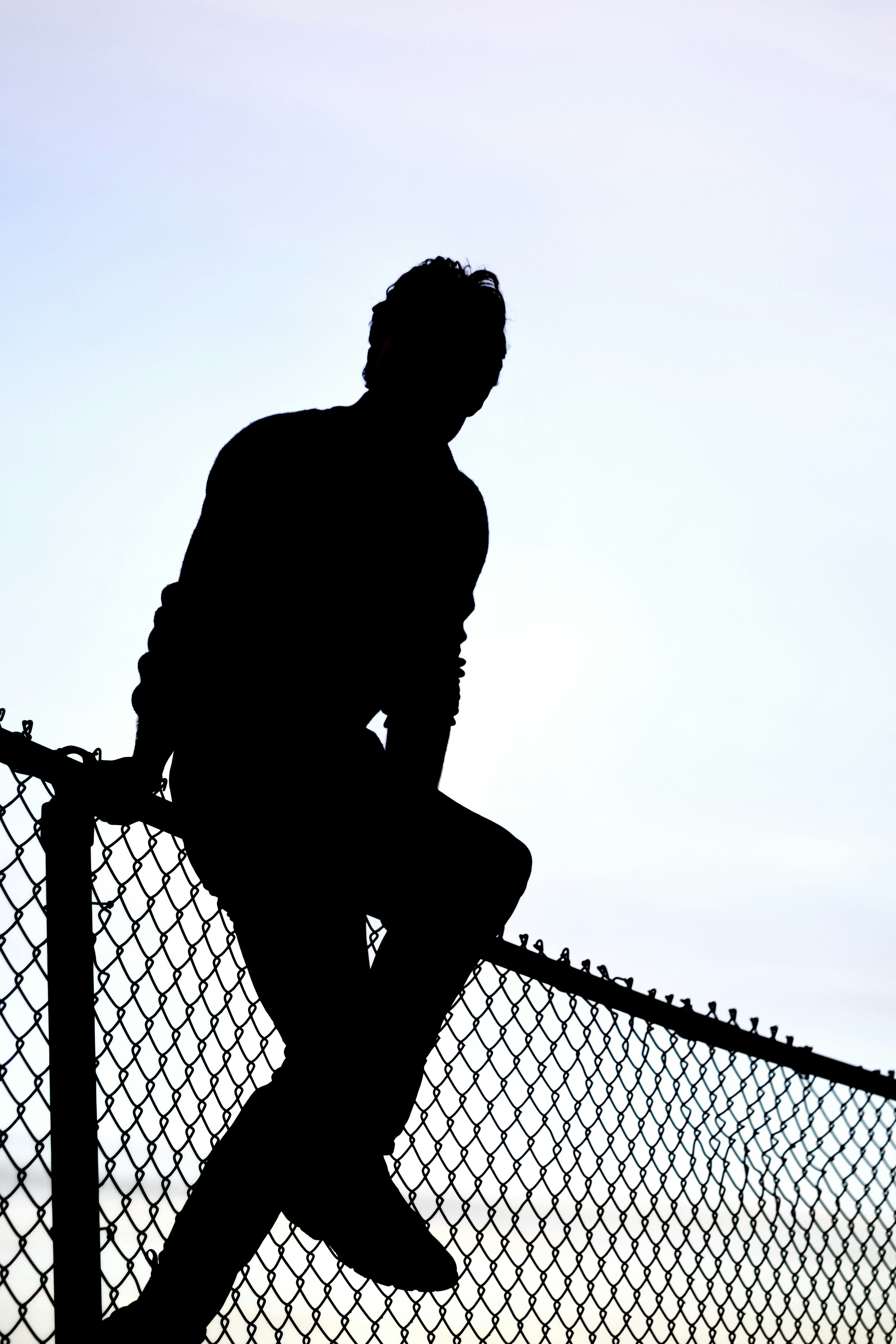 Silhouette of a person sitting on a fence