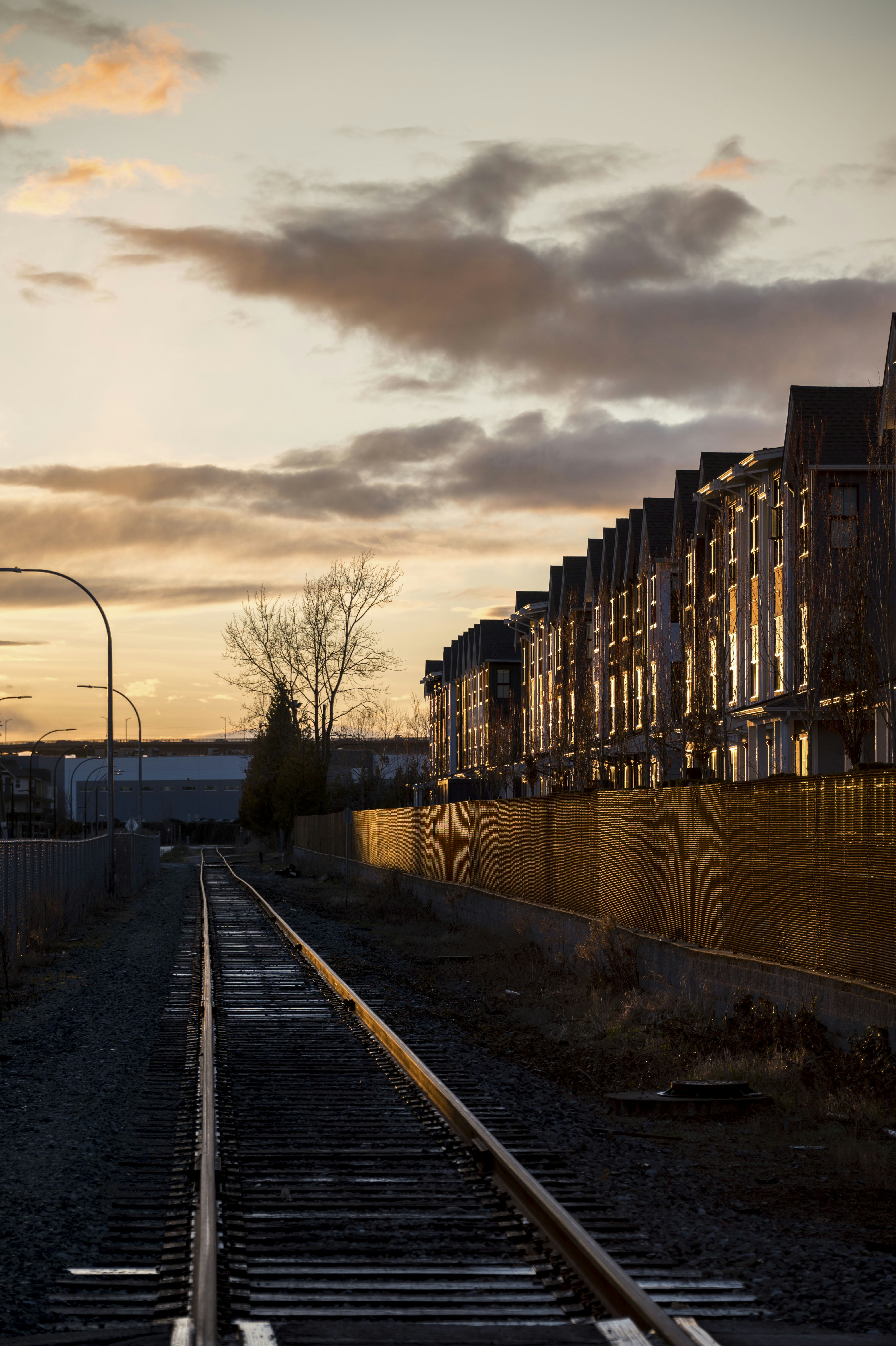 Train tracks lead past row houses at sunset