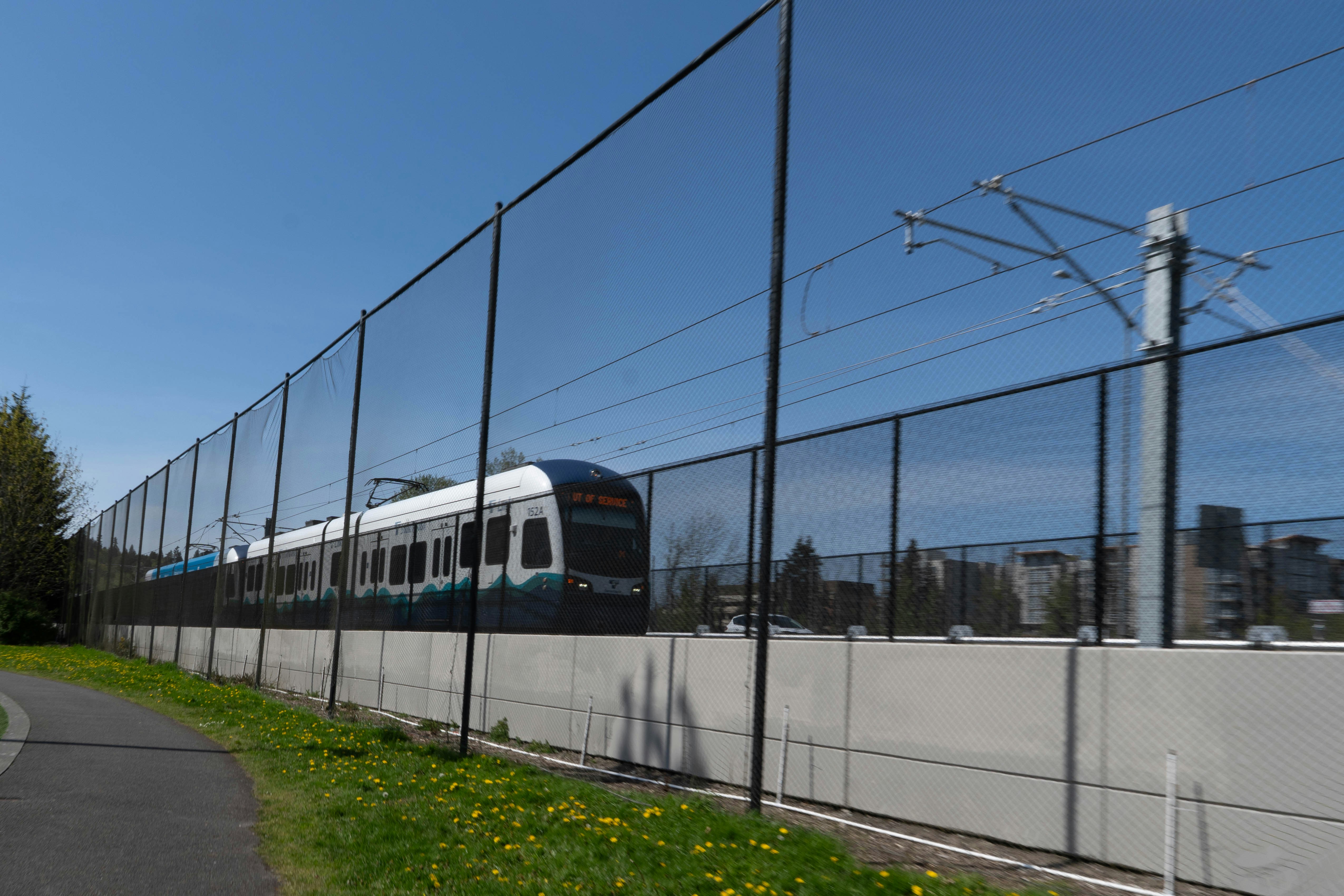 A train passes by a fence on a sunny day.