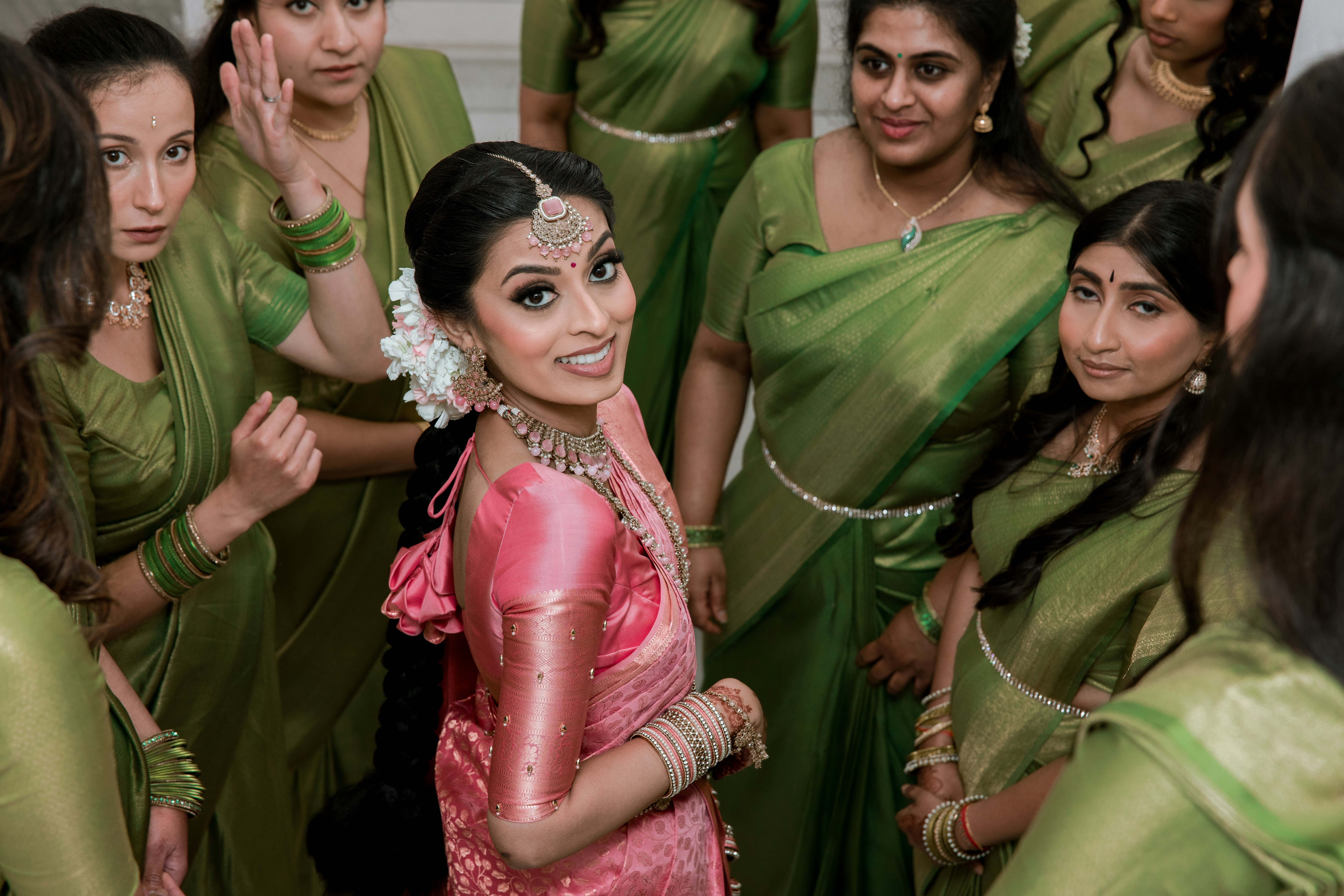 Bride in pink sari with bridesmaids in green saris