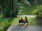 Two people sitting on a bench by a lake.
