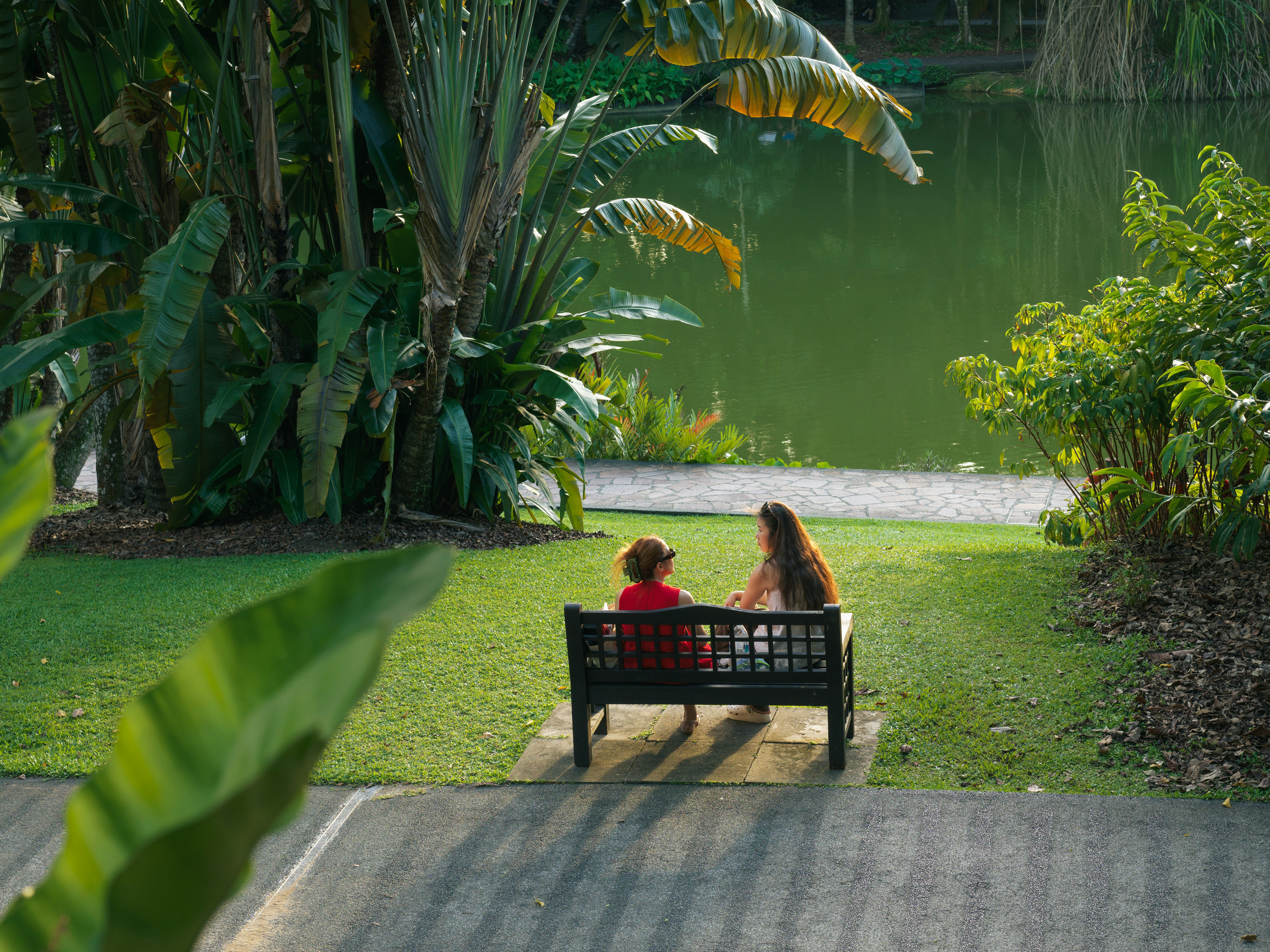 Two people sitting on a bench by a lake.