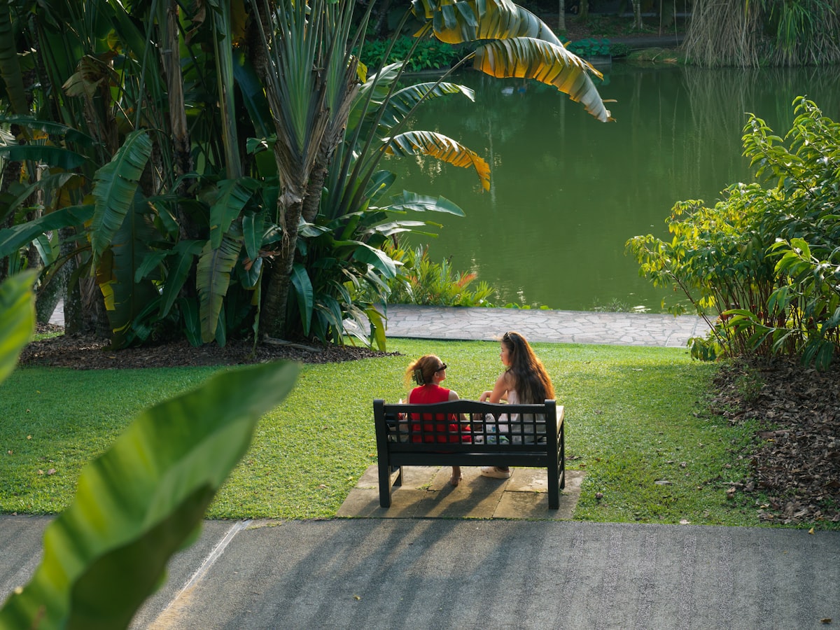 Two people sitting on a bench by a lake