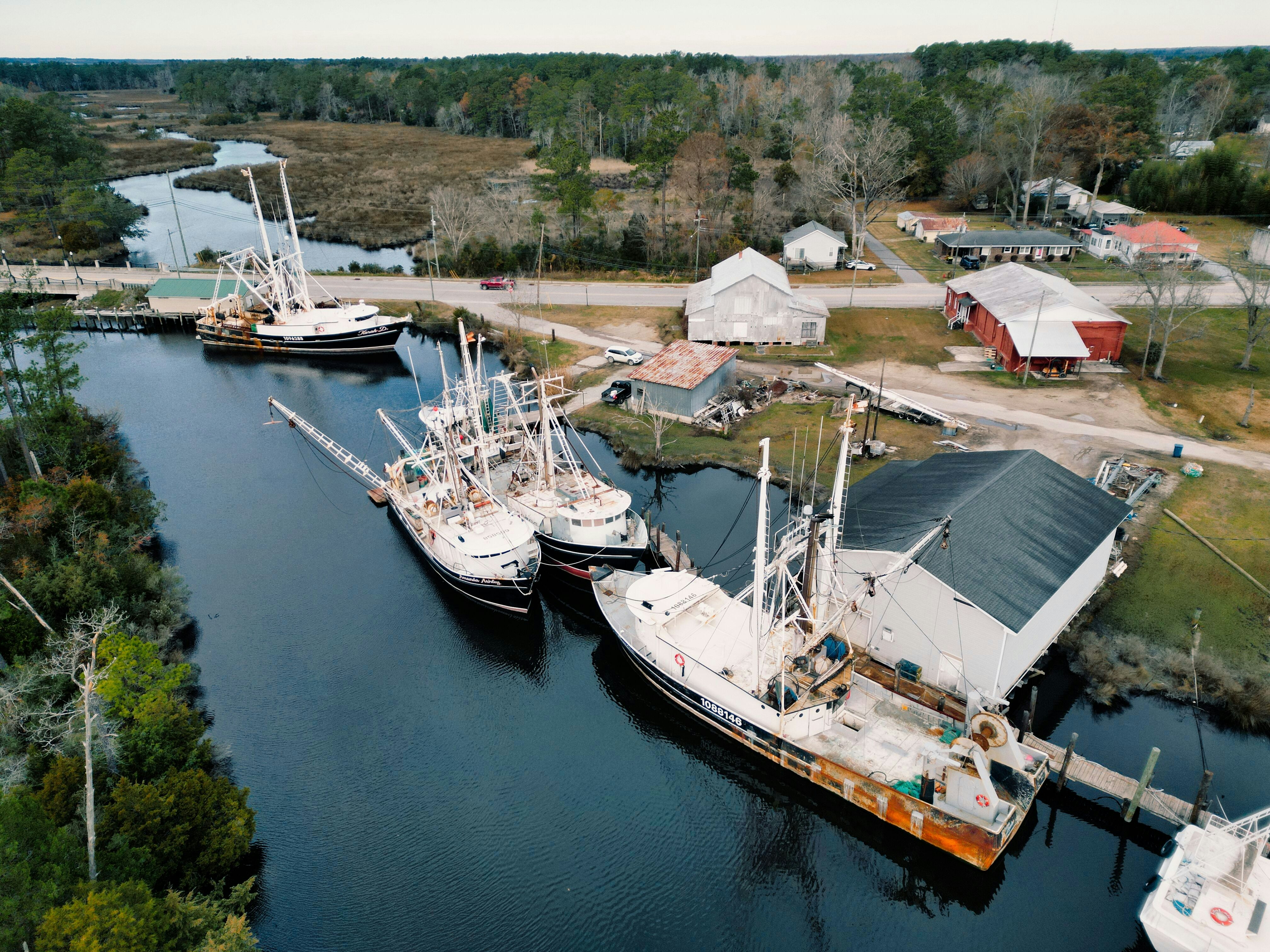 Barcos de pesca atracados en un estrecho canal cerca de edificios.