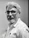 Man with glasses and beard in a white shirt.