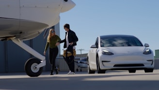 Couple walking towards a white car next to airplane