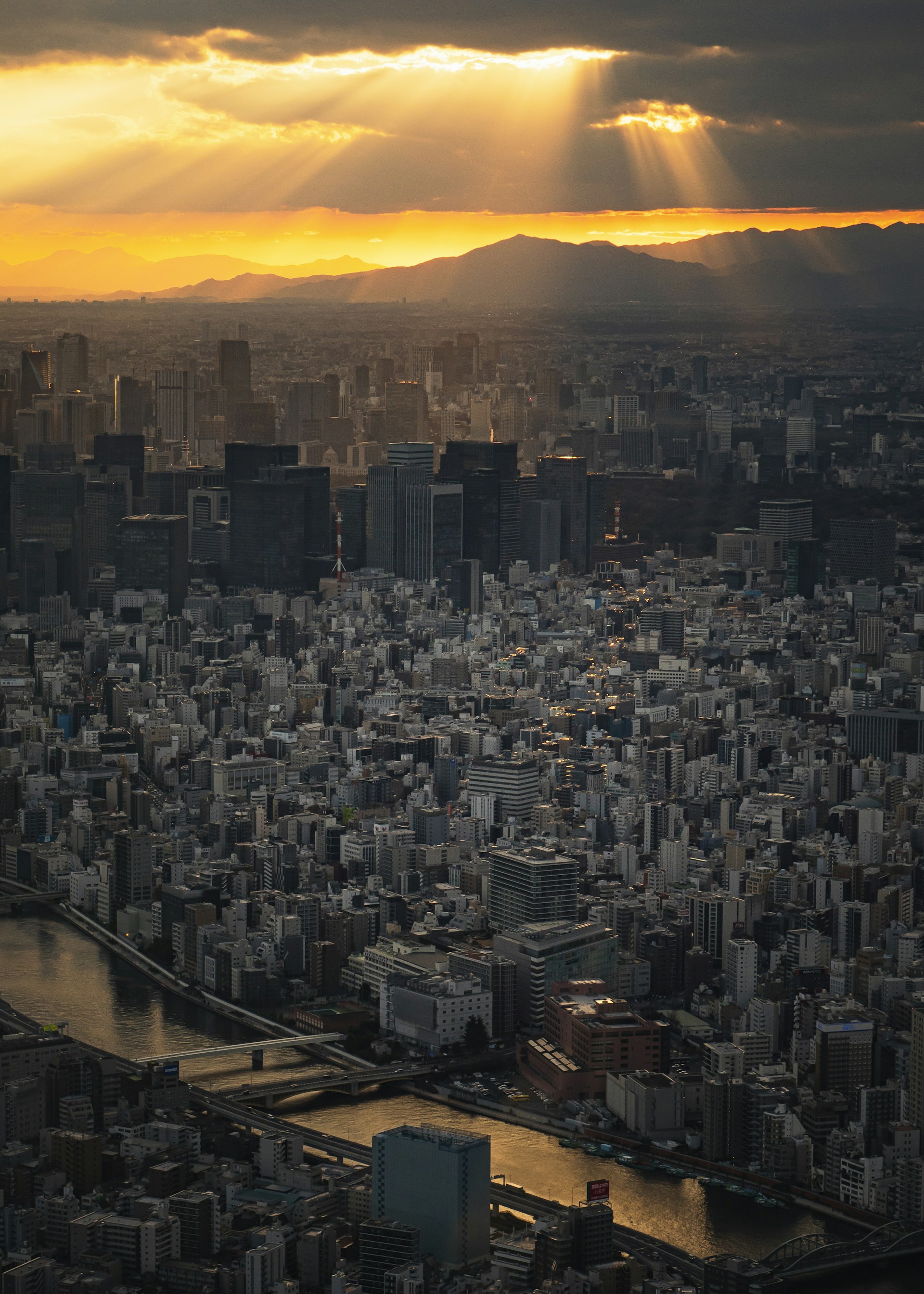Sunbeams shine over a sprawling cityscape at sunset.