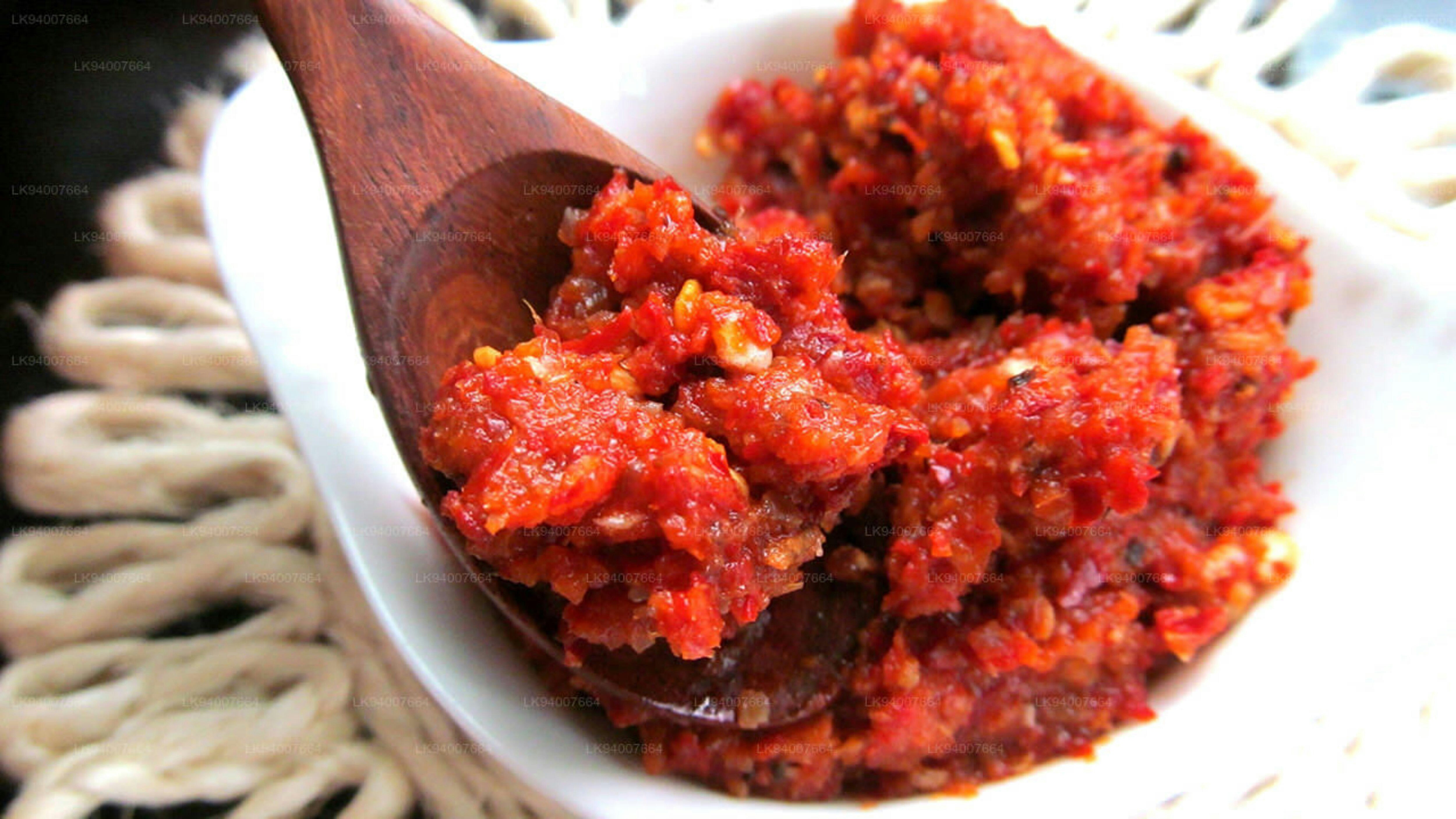 A wooden spoon scoops spicy red chili paste.