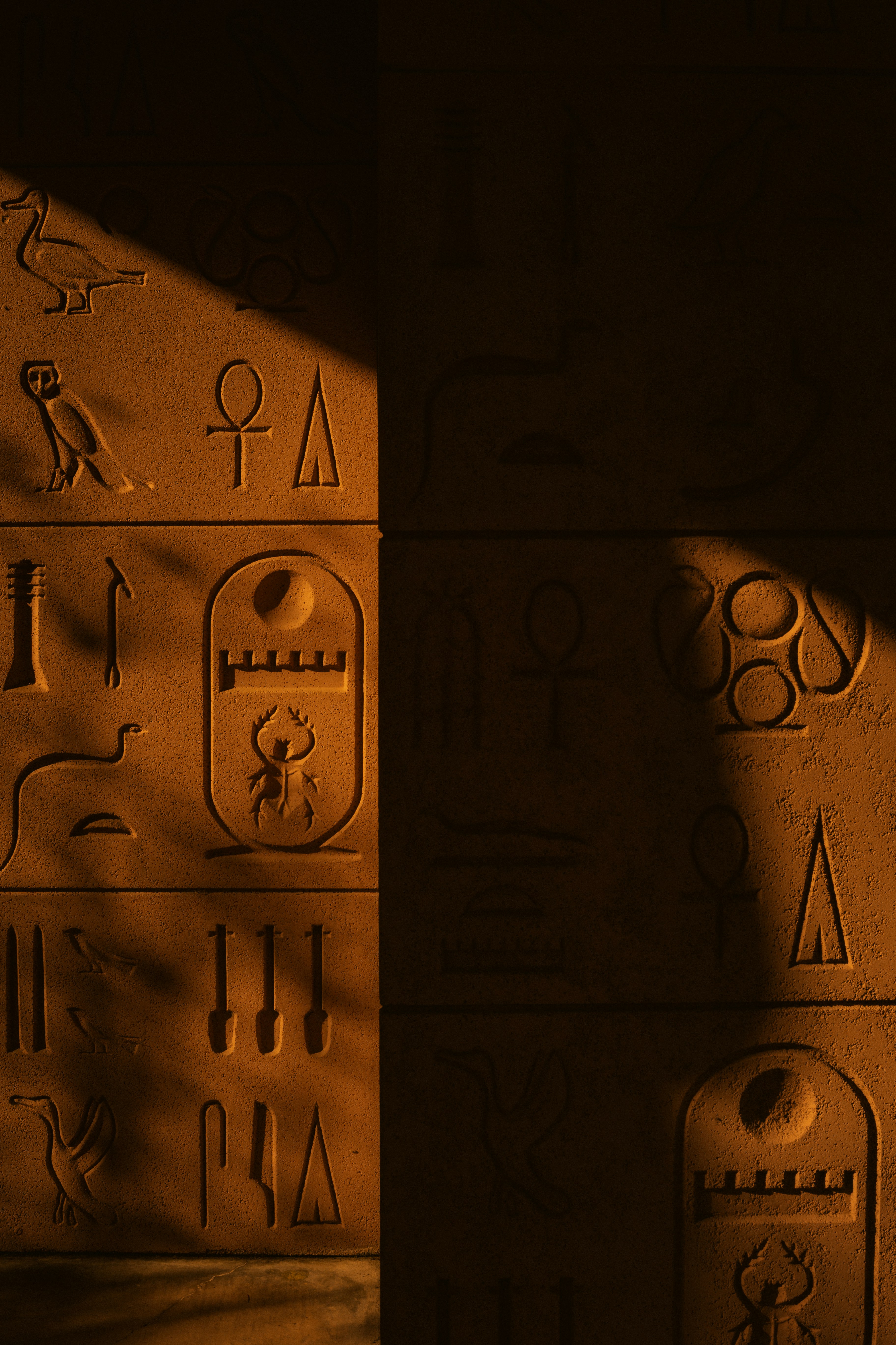 Ancient egyptian hieroglyphs carved into stone wall.