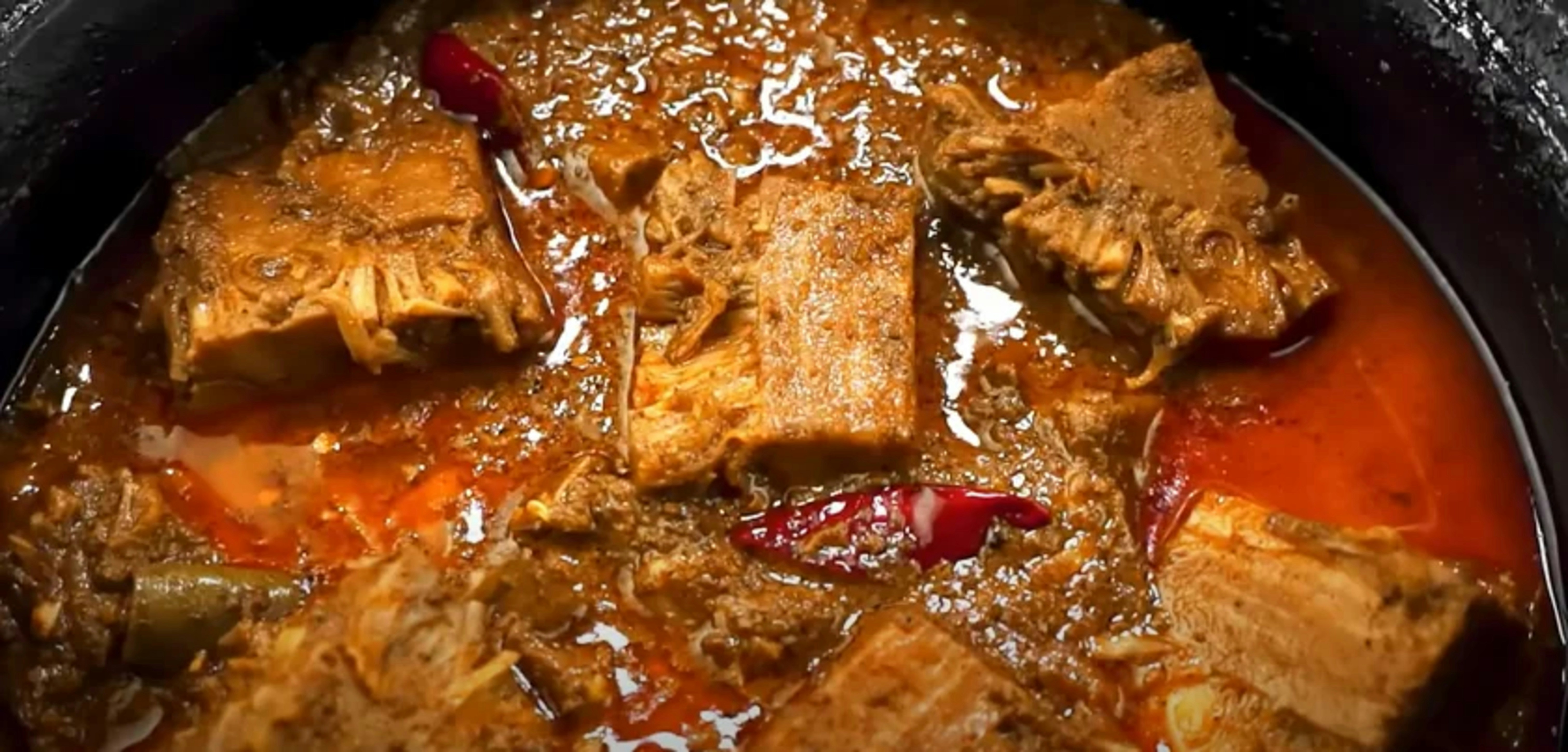 Hearty stew with chunks of meat and red chili peppers.