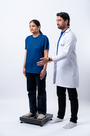 Doctor weighing a young woman on a scale