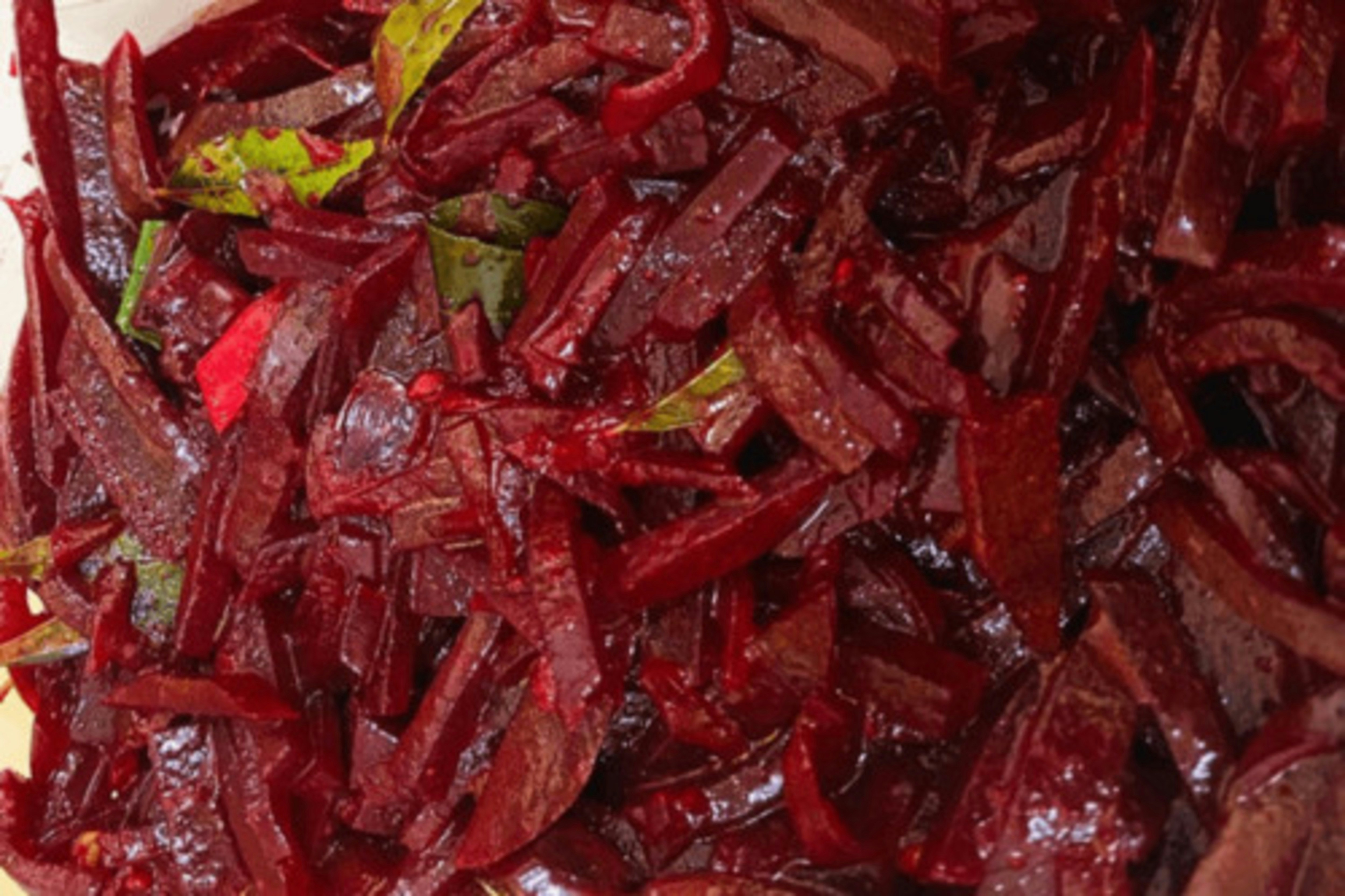 Chopped beets with green leaves, close-up view.