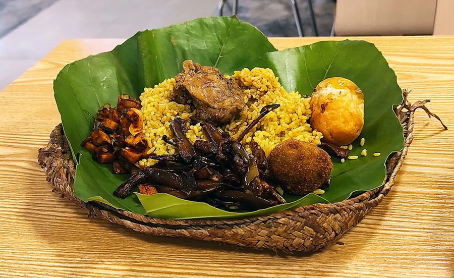 Yellow rice served with meat and egg on a banana leaf