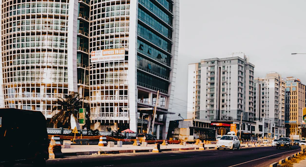 Modern buildings line a city street with cars.
