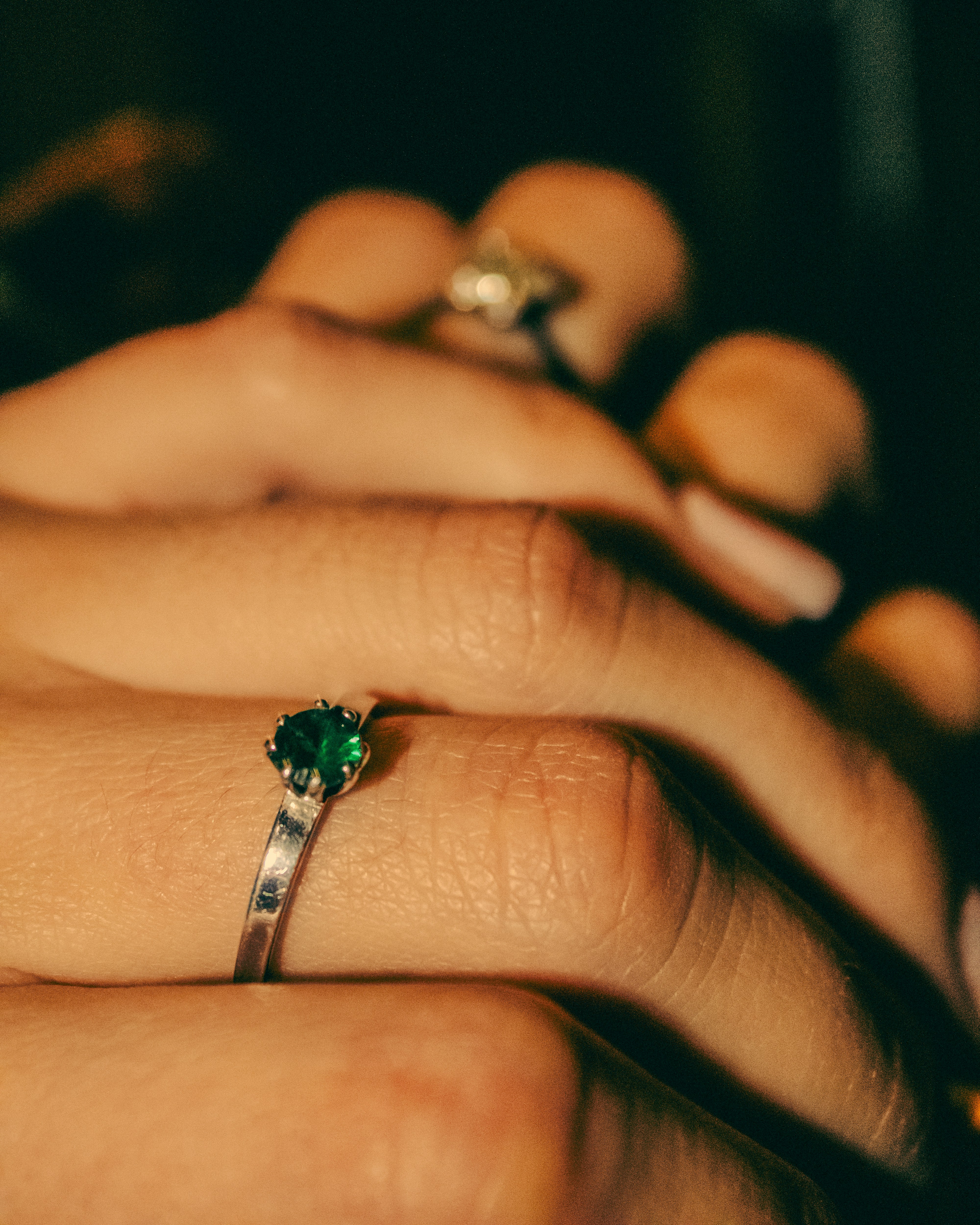 Nahaufnahme einer Hand, die einen smaragdgrünen Ring trägt