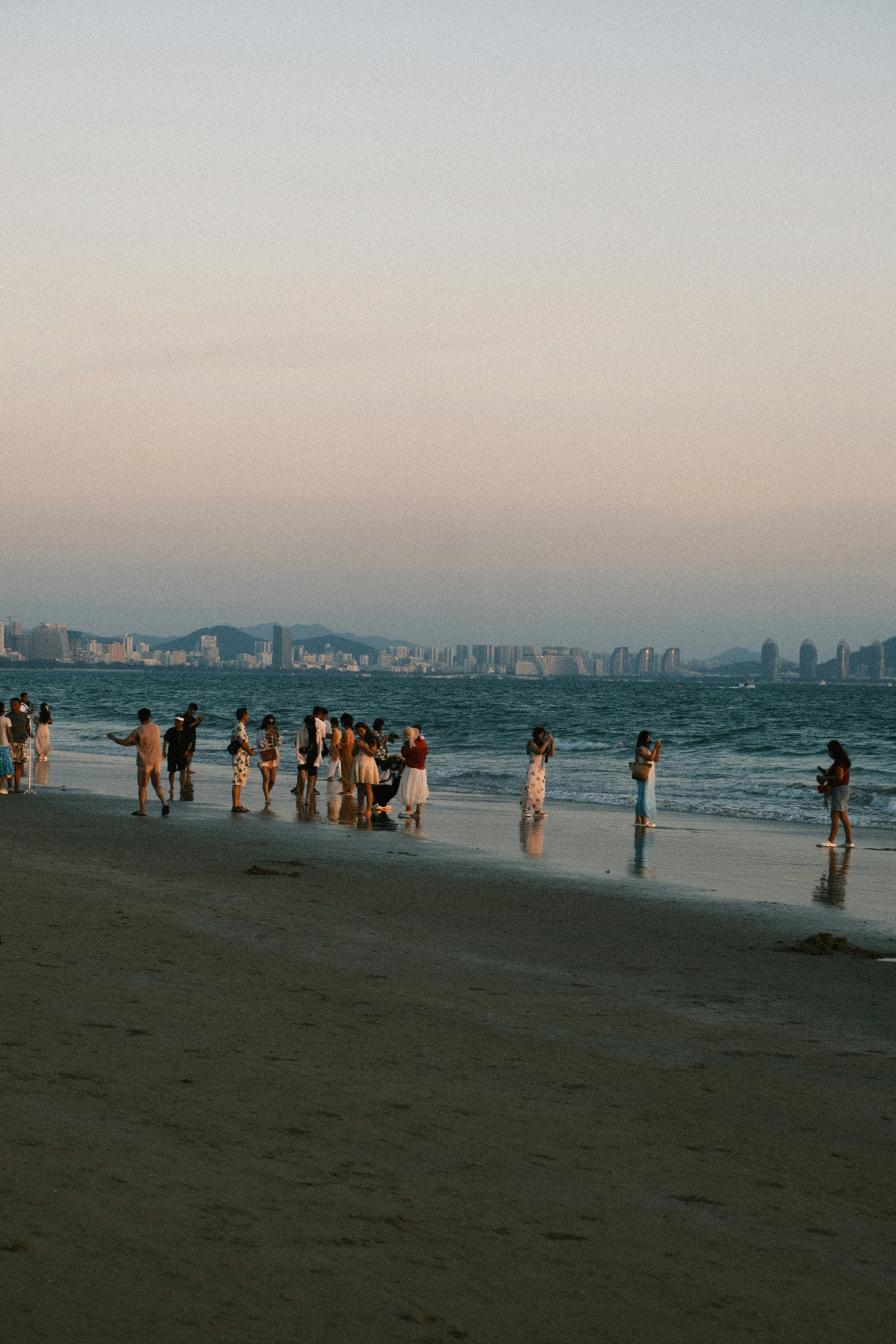 People on a sandy beach with city skyline background.