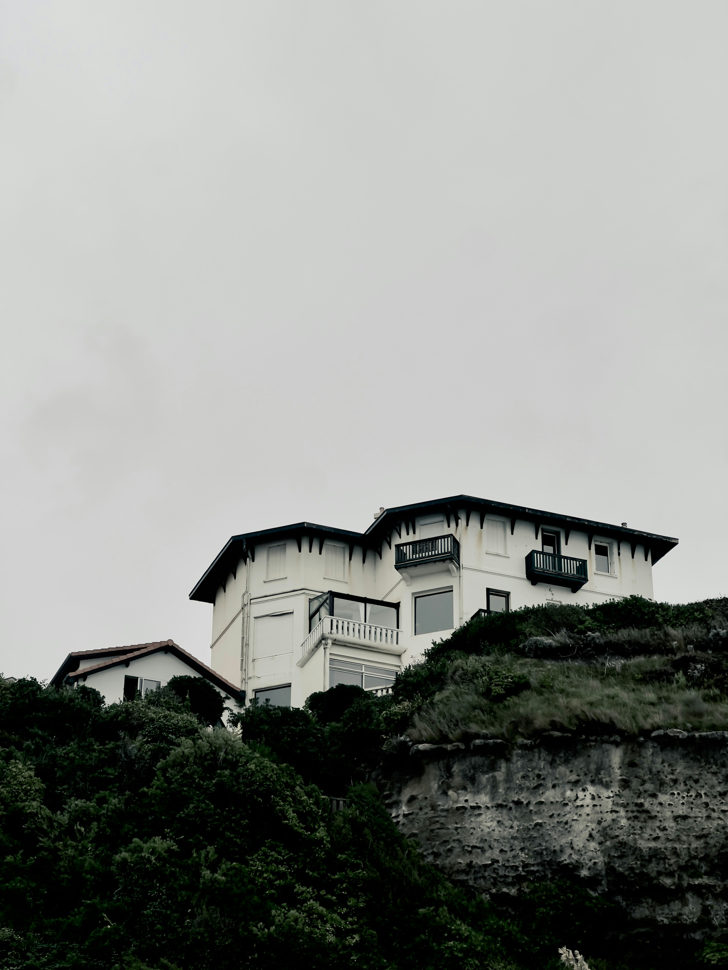 White house on a green, rocky hill.