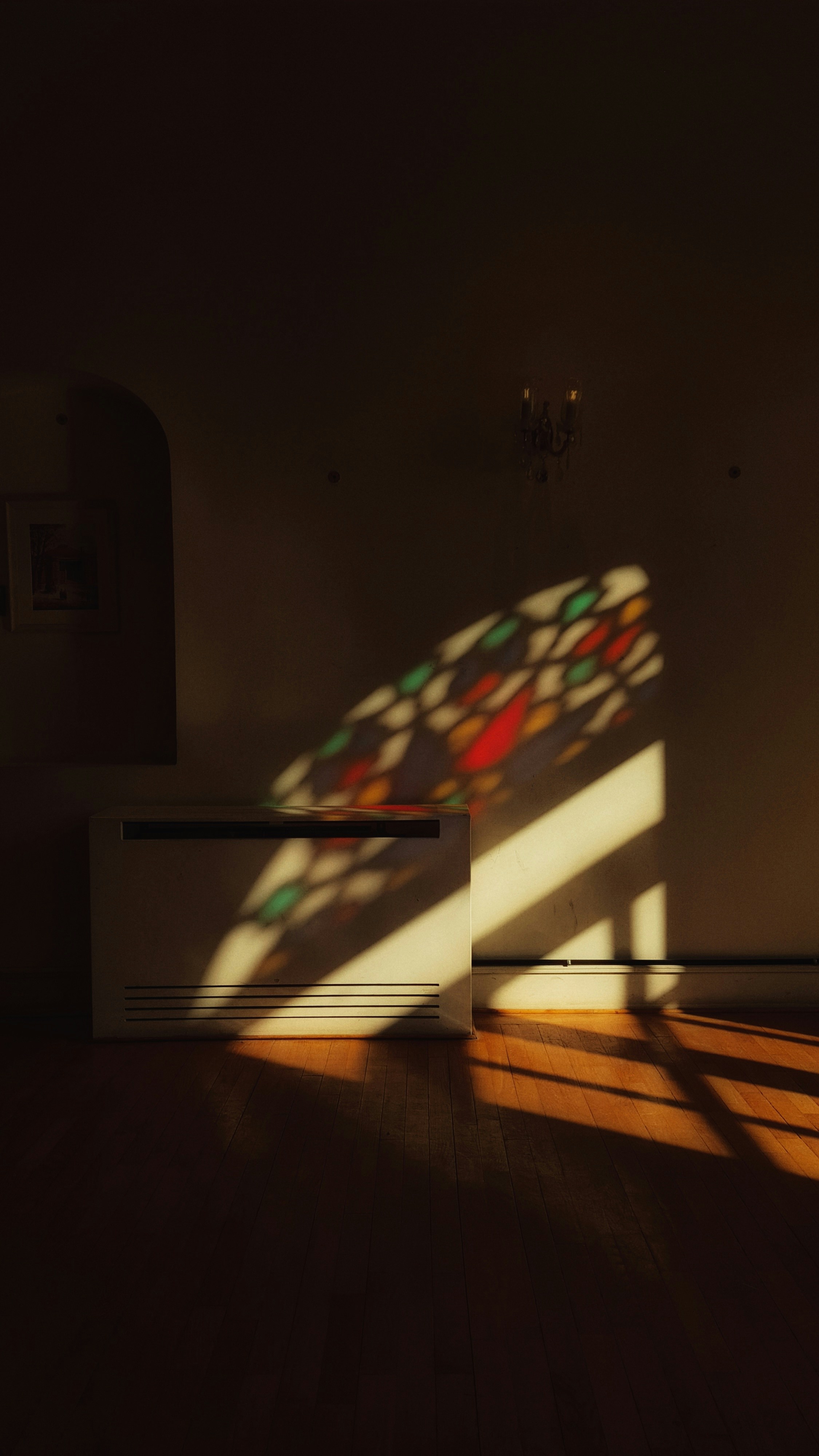 La luz del sol proyecta patrones de vidrieras coloridas en las paredes.