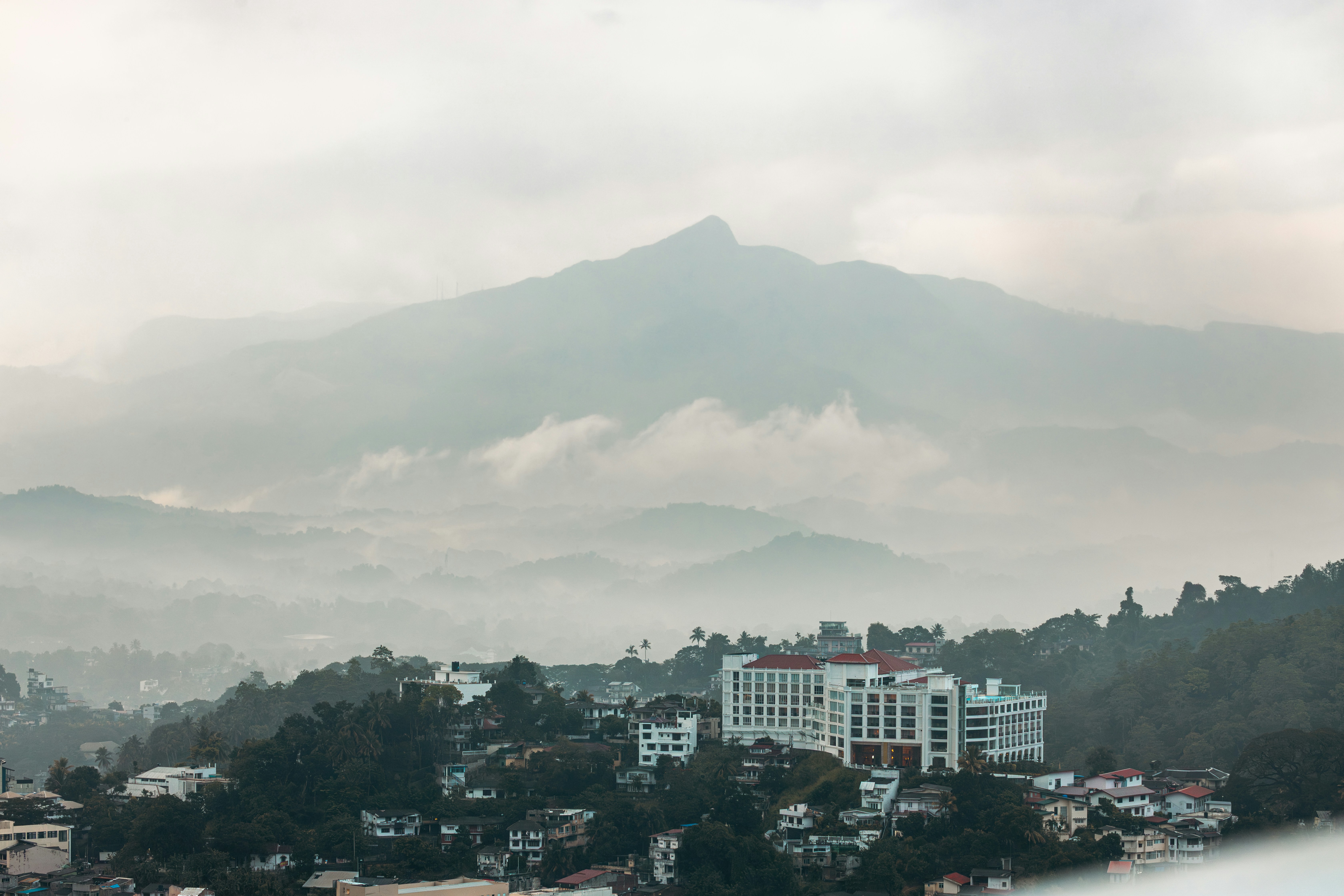 Misty mountains loom over a town with white buildings.