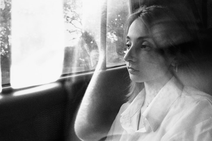 A person at a window with blurred trees beyond, gentle natural daylight, anonymized framing