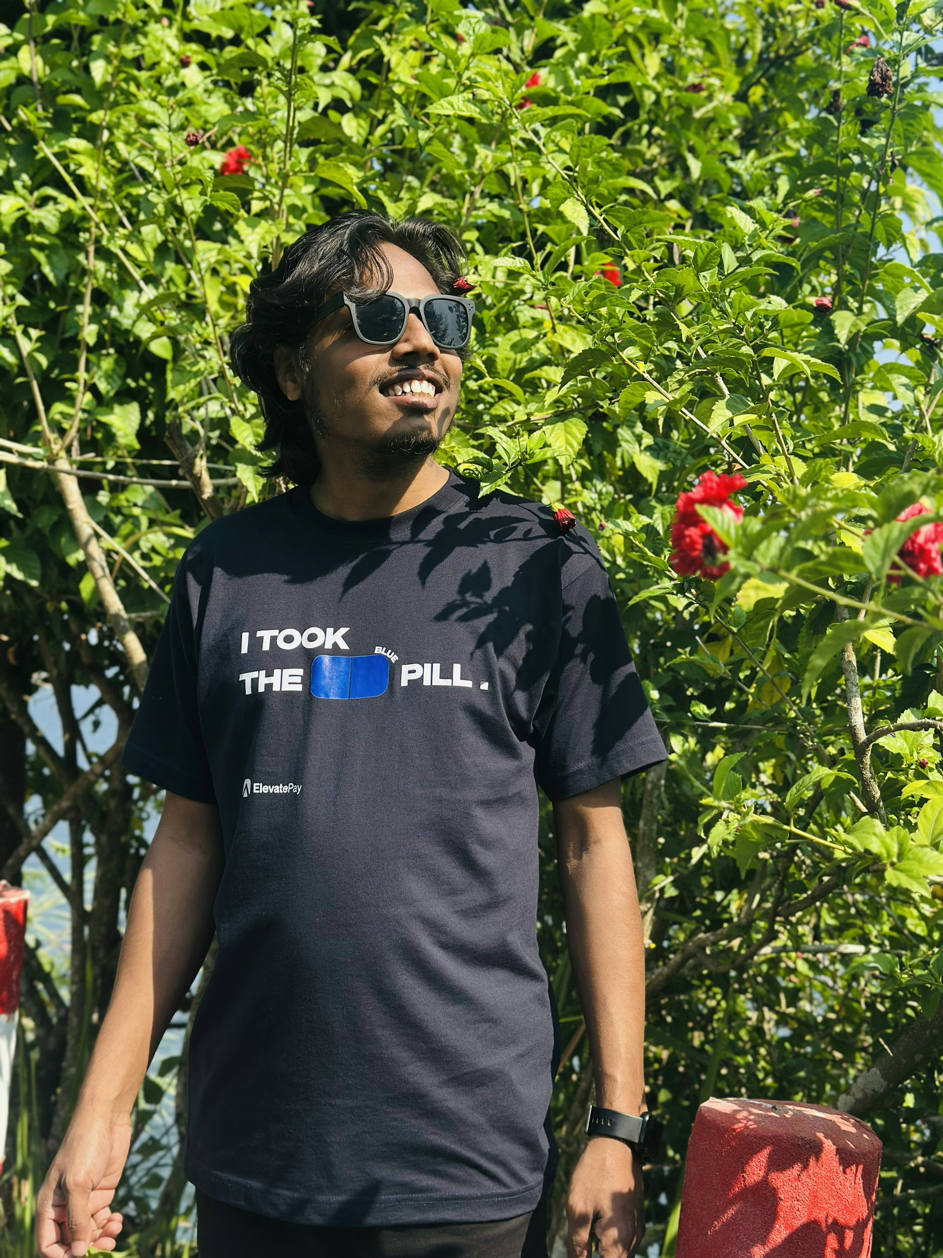 Man in a t-shirt with text standing outdoors.