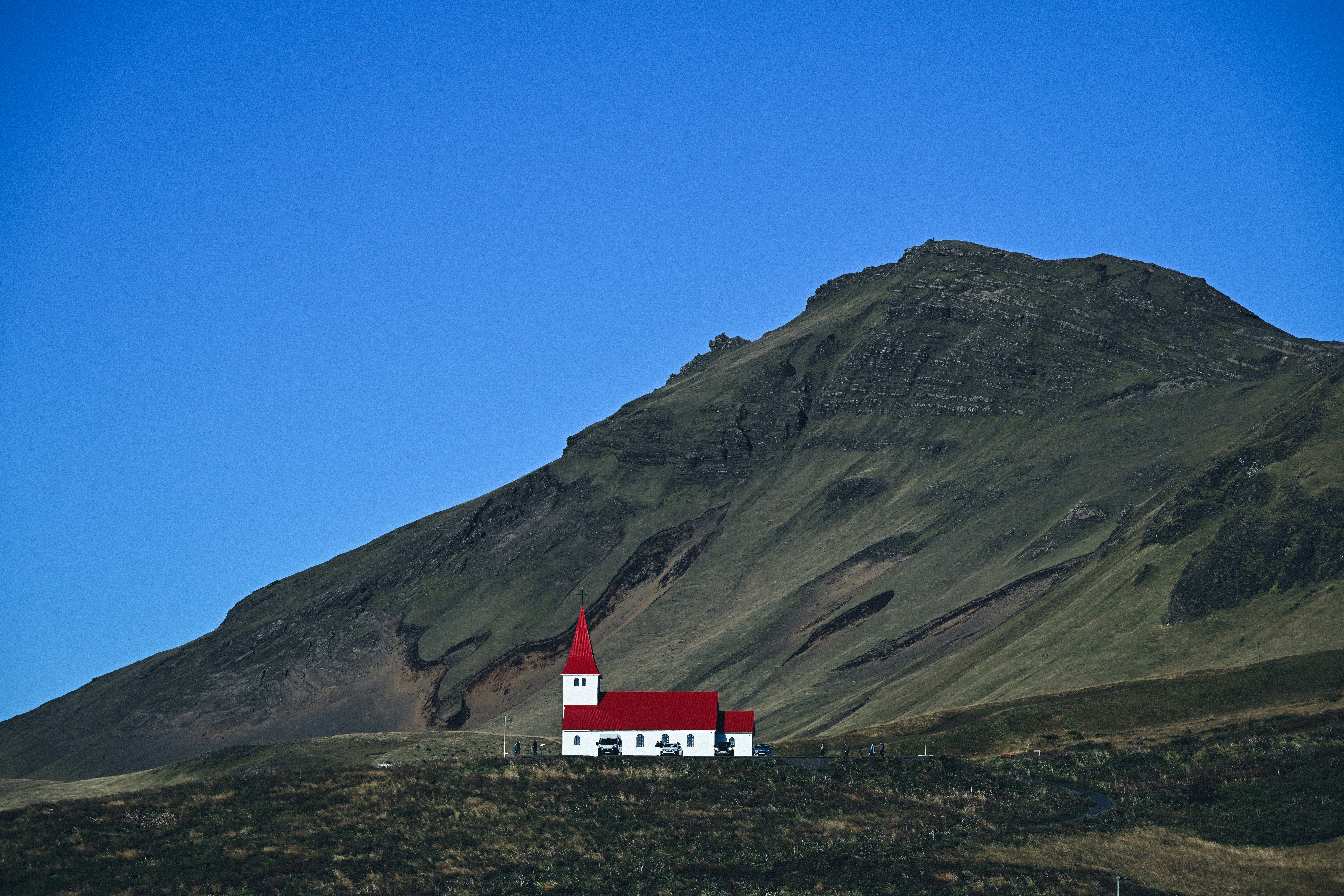 White church with red roof on a hill.