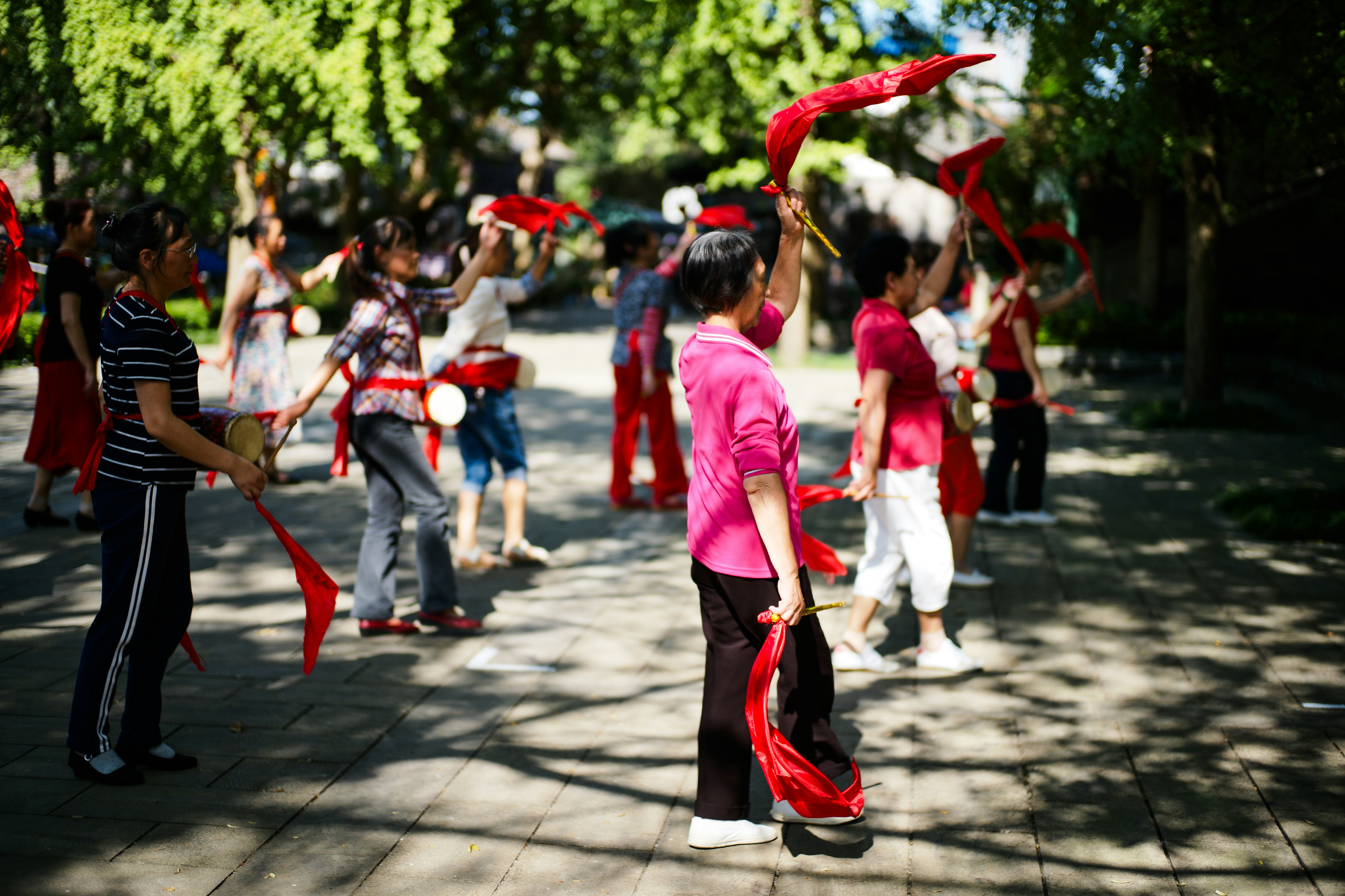 Children practicing traditional dance with red ribbons outdoors