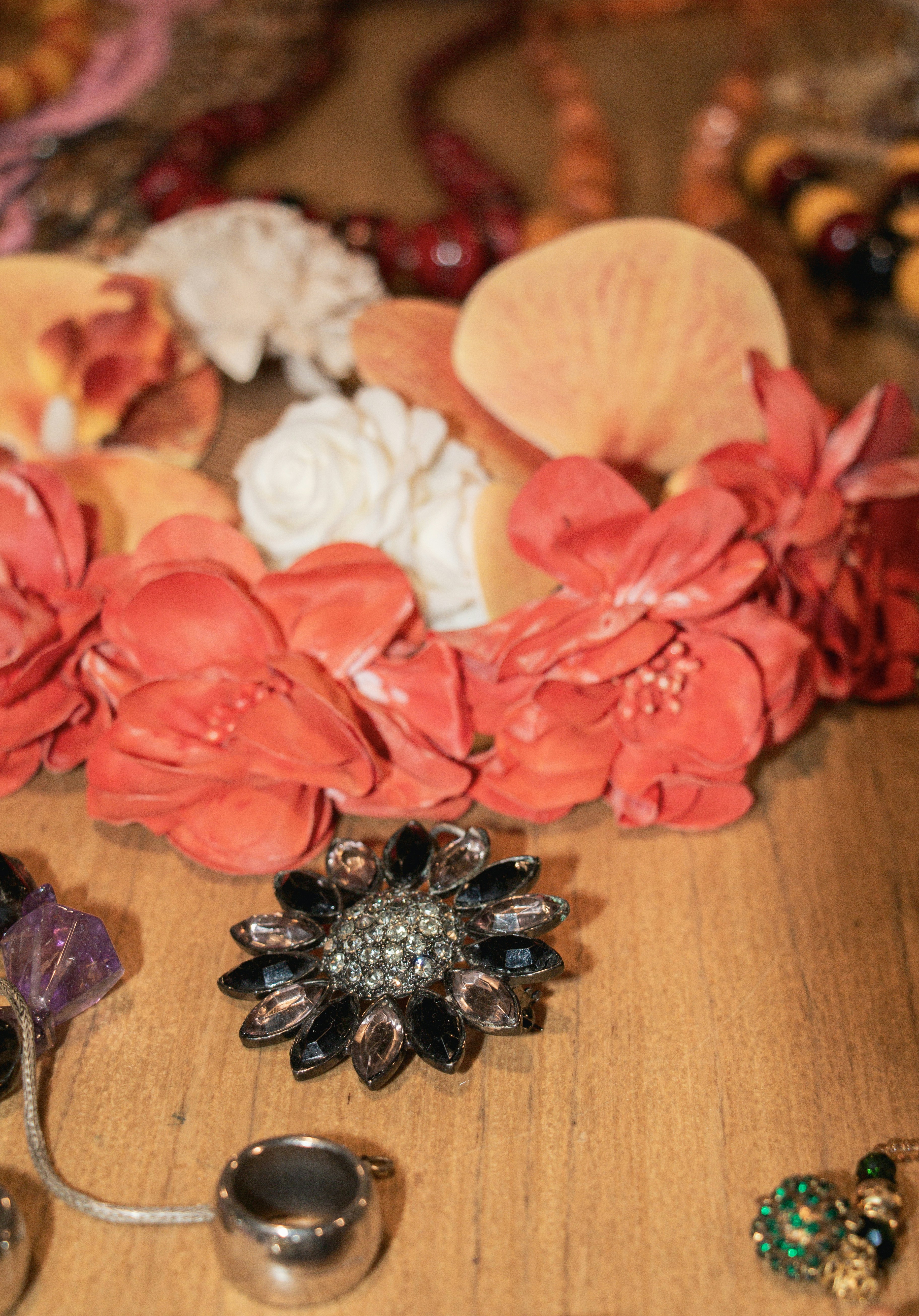 Assortment of colorful flowers and jewelry on a wooden surface.
