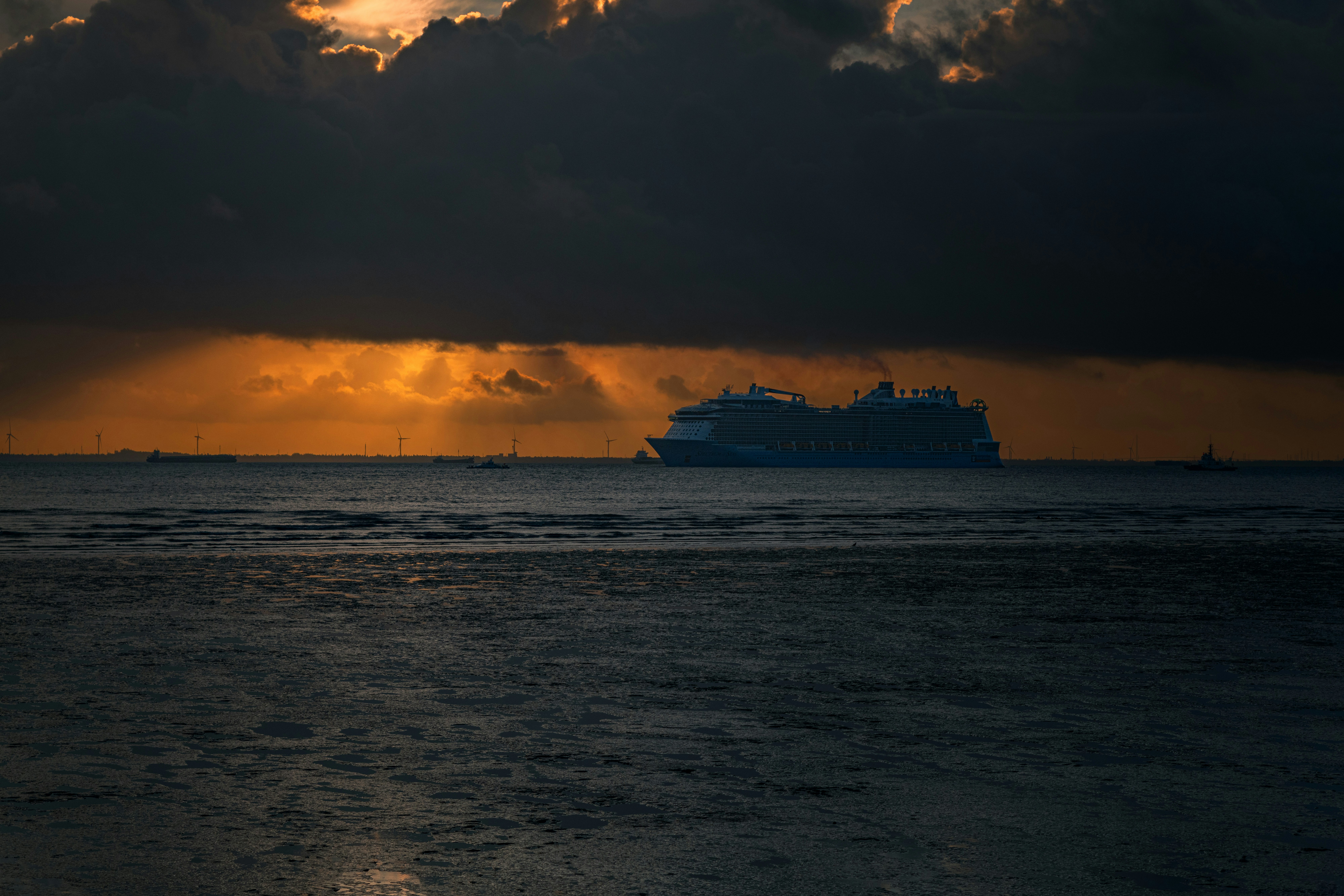 クルーズ船は劇的な夕焼け雲の中を海の上空を航行します。
