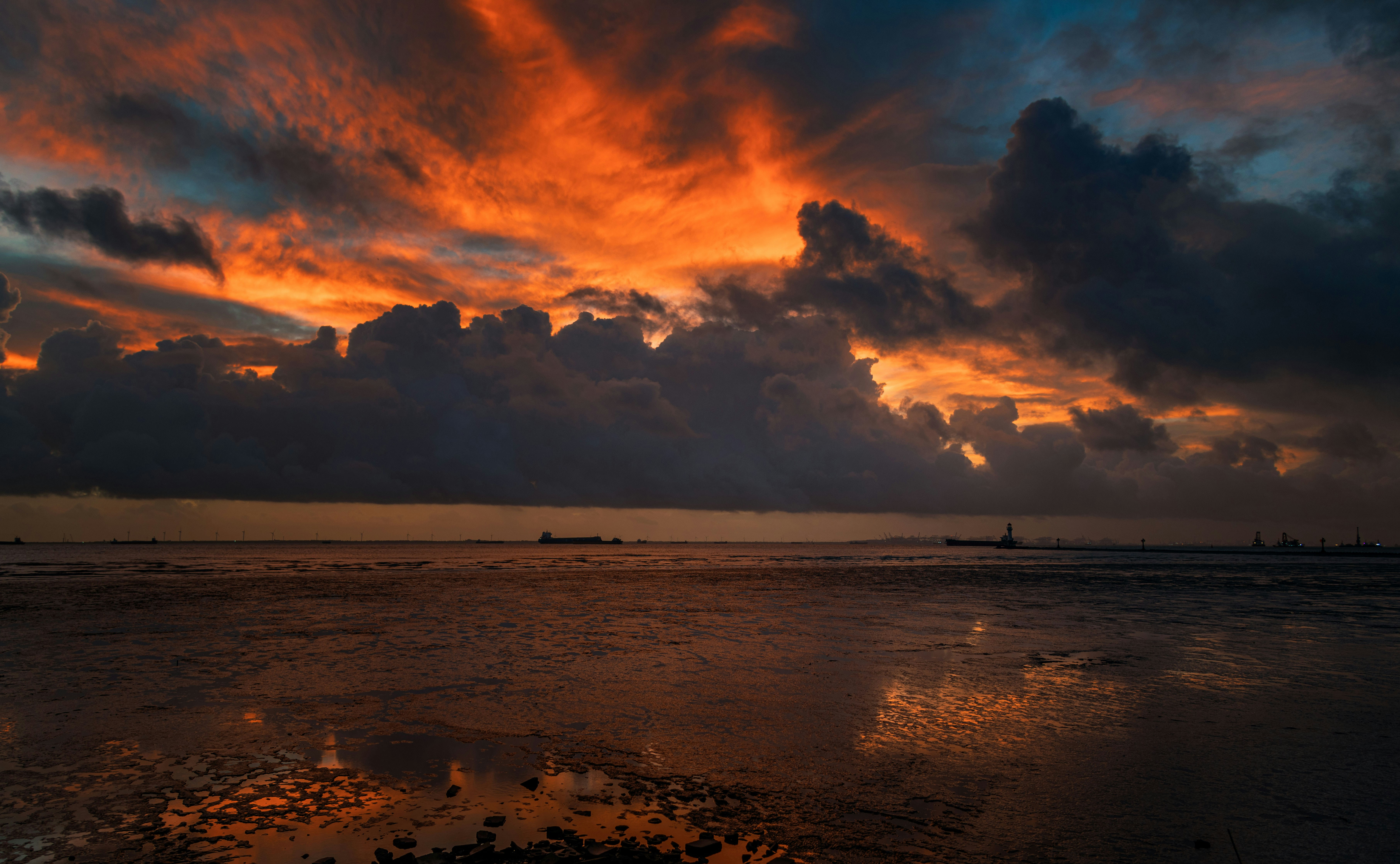 穏やかな海の反射の上に劇的な夕焼けの雲が広がる