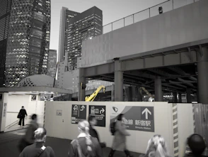 People walking past construction site with skyscrapers behind