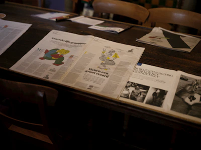 Newspapers and magazines on a wooden table.