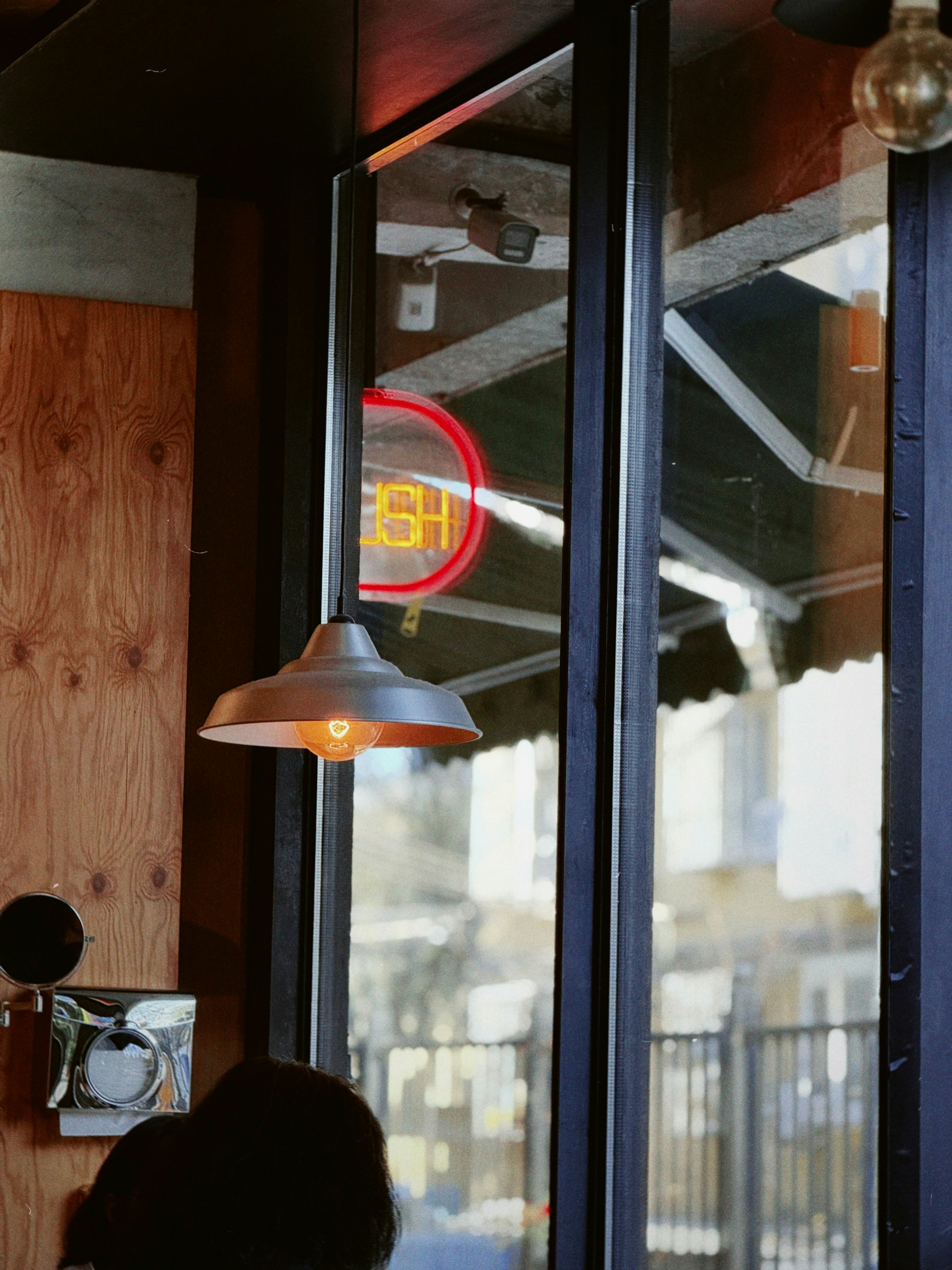Industrial lamp hangs in front of window reflection.