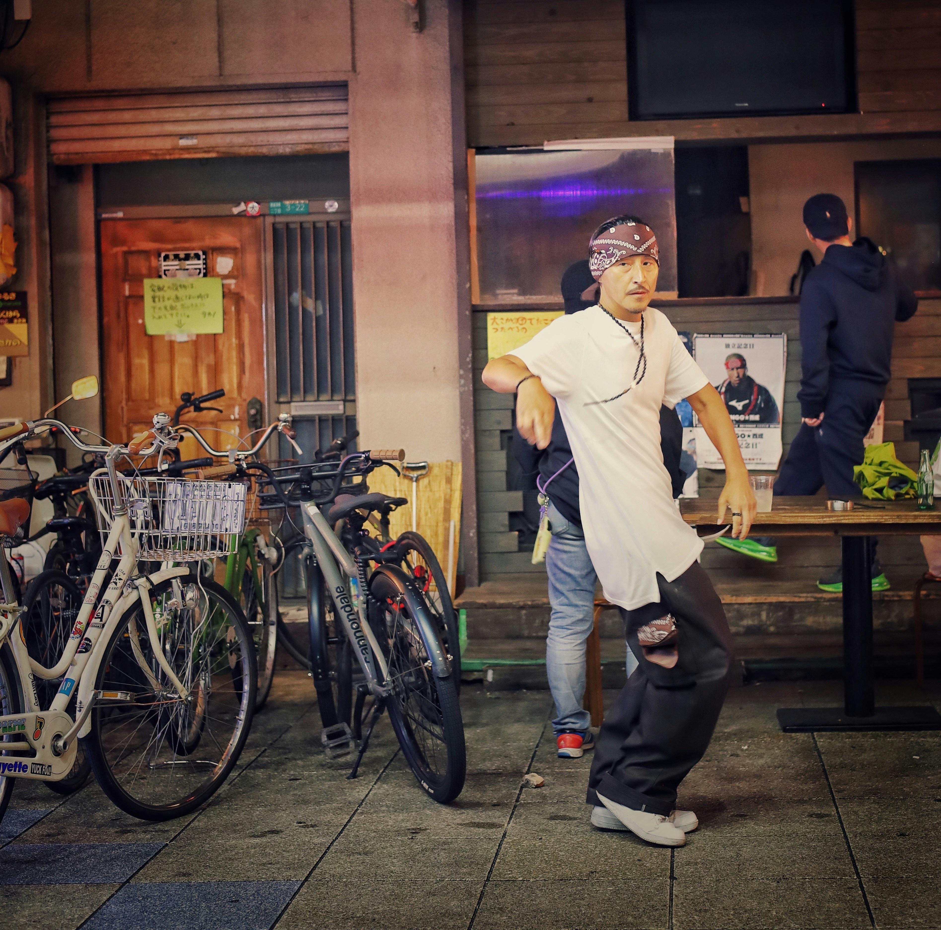 Man in bandana and white shirt dances outdoors