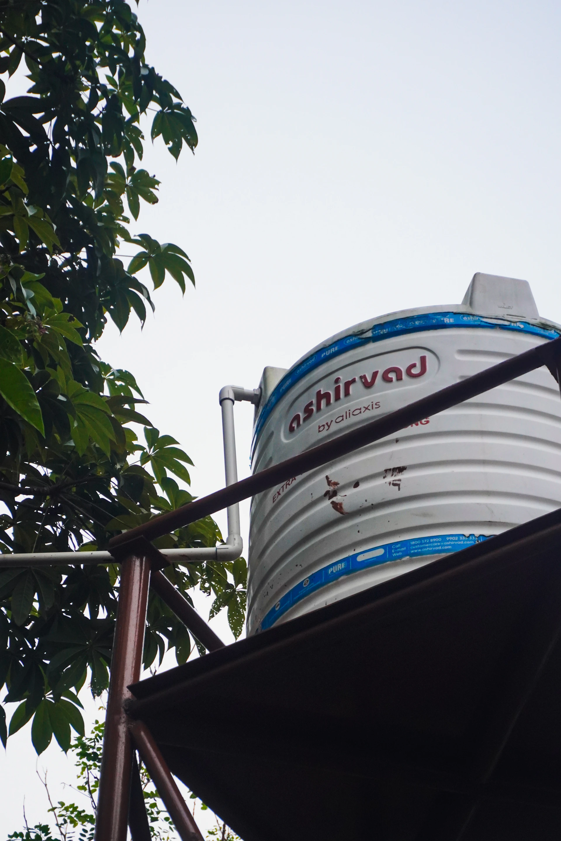 Water tank with green leaves and overcast sky.