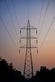 Silhouette of a power pylon against a twilight sky.