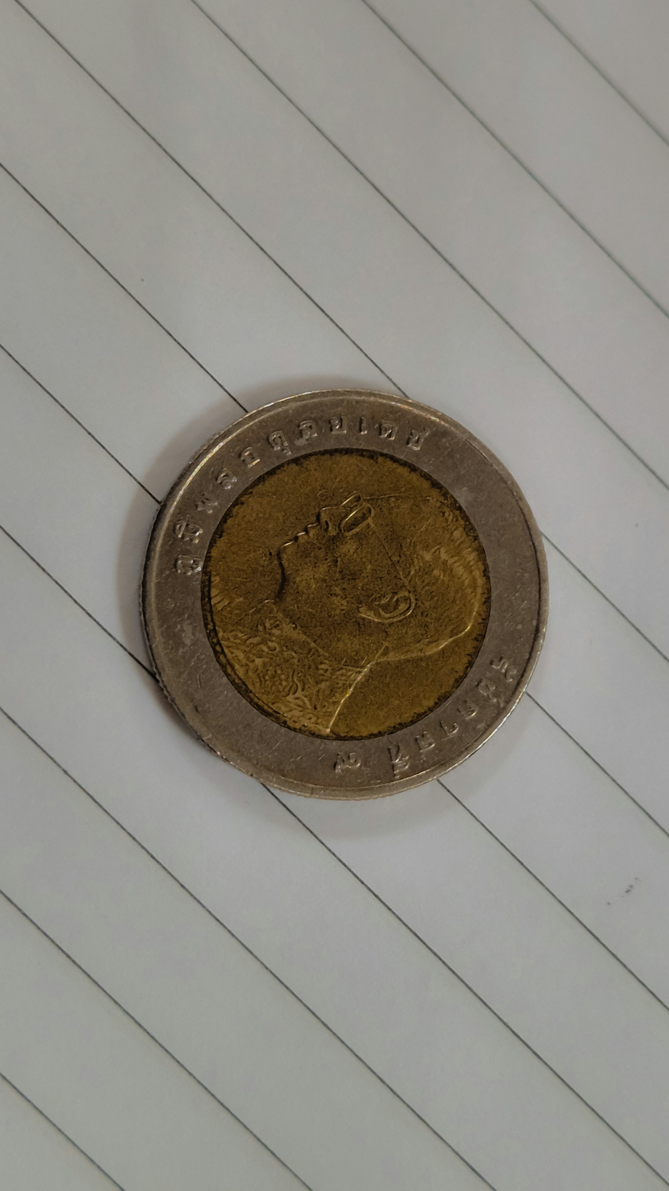 A gold and silver coin with a profile.